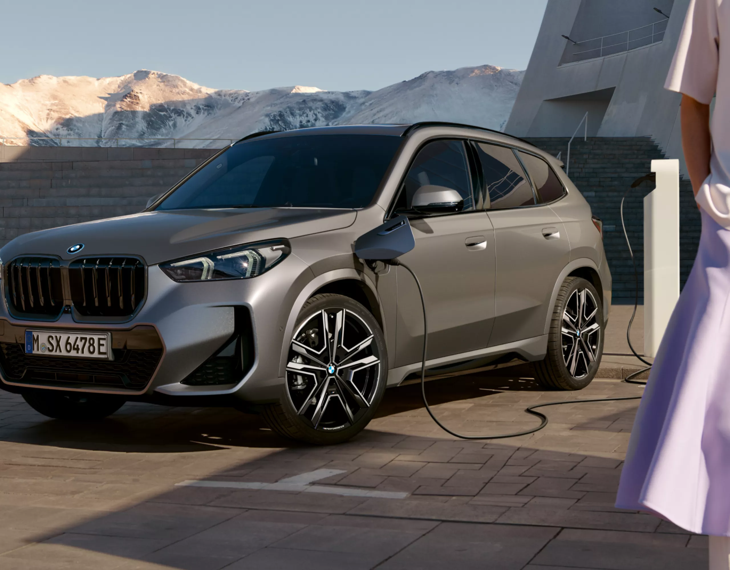 Ein BMW wird an einer öffentlichen Ladestation mit Bergen im Hintergrund aufgeladen