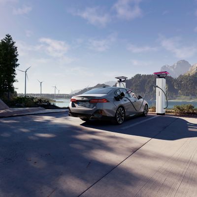 BMW charging at a charging post with views of water, mountains and wind turbines