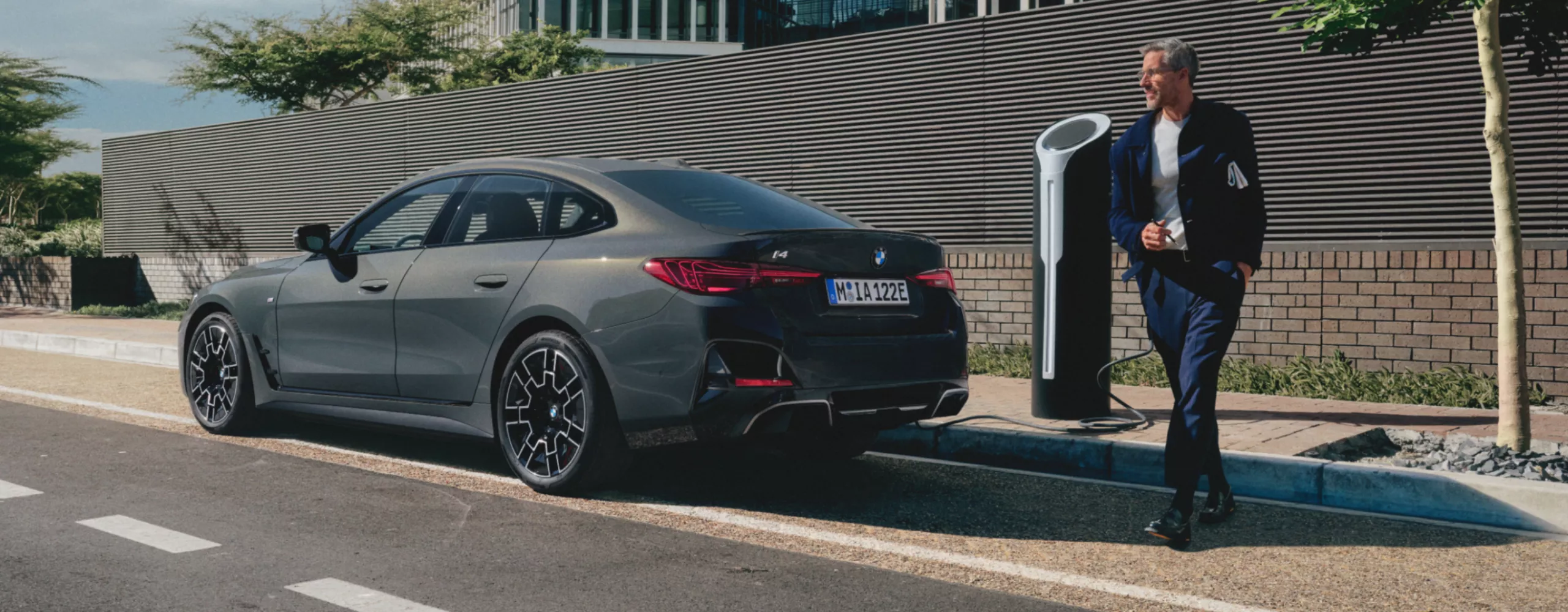 Person som står bakom en laddande BMW vid sidan av vägen