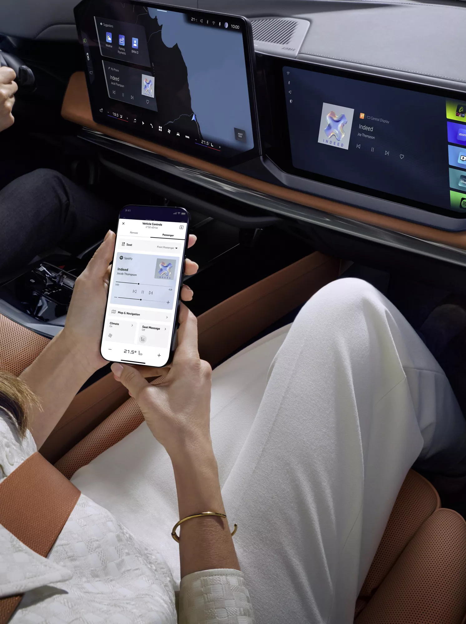 女性がBMW i7に座り、スマートフォンの「My BMW」アプリを見ています。