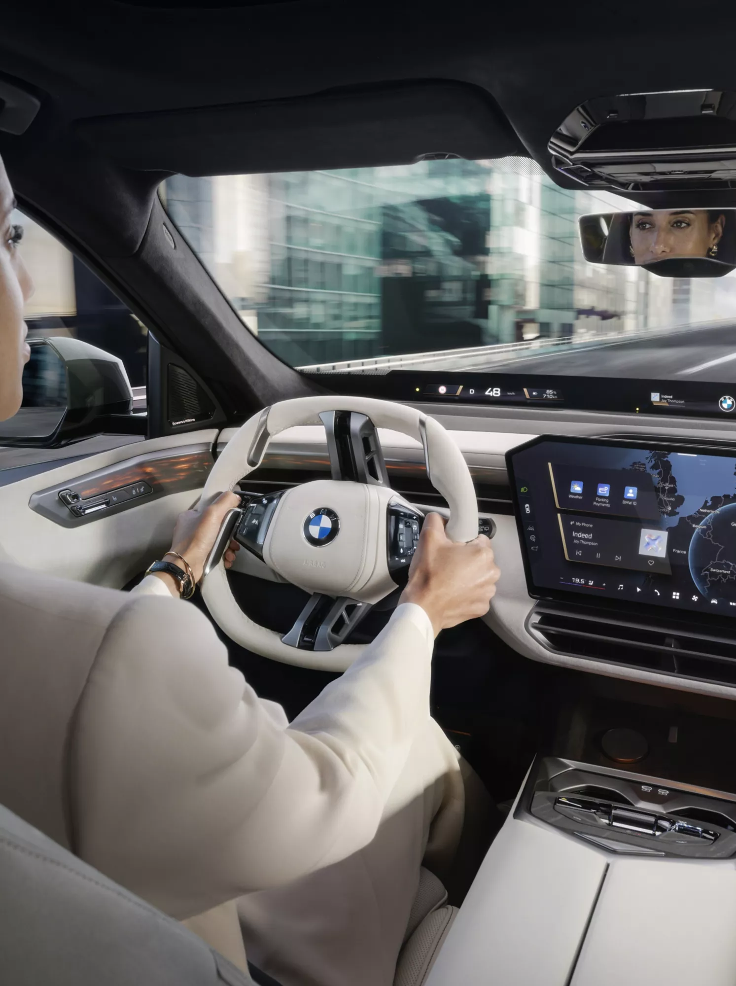 女性がBMW iX5を運転し、ディスプレイに表示される指示に従っている。