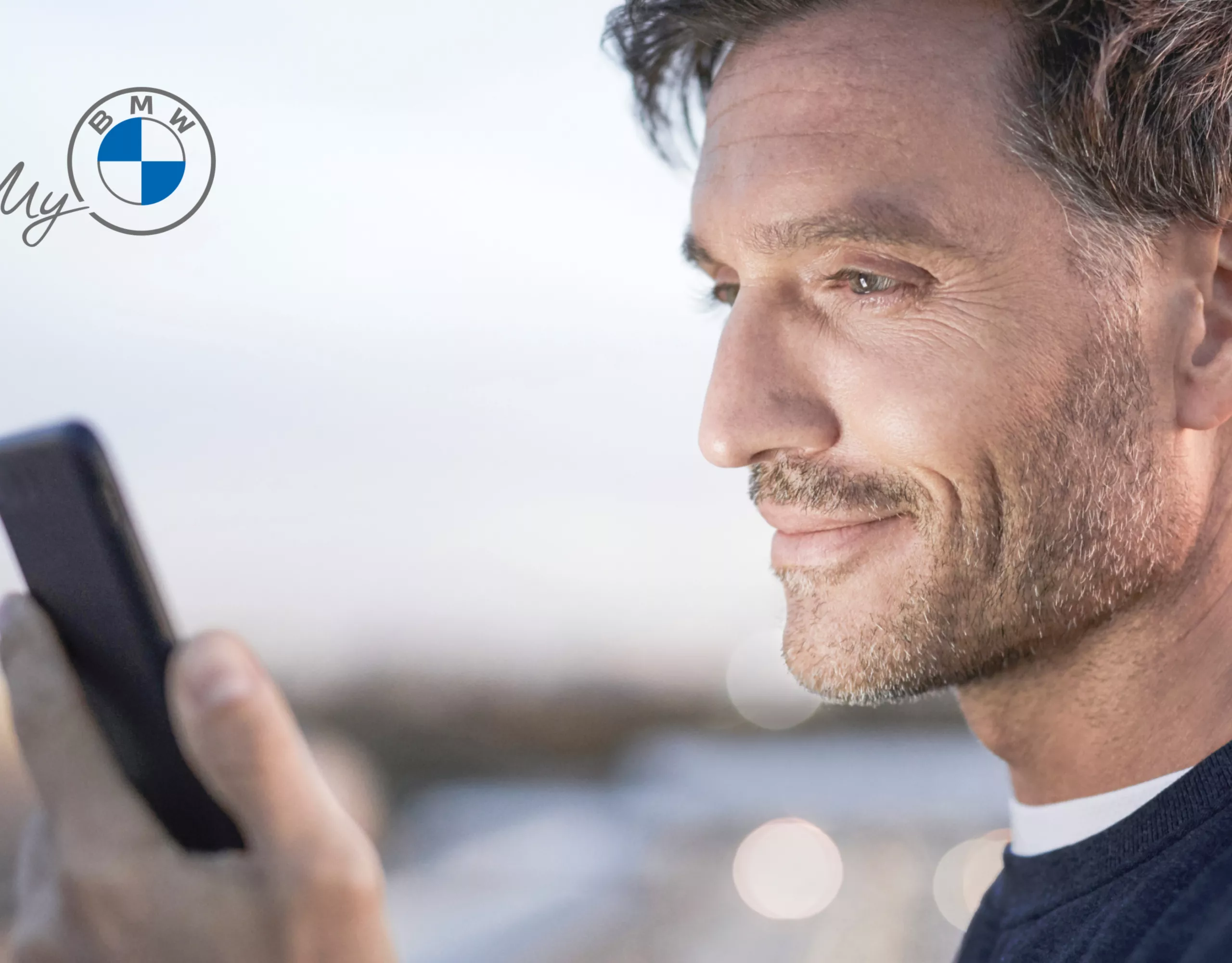 Ein Mann überprüft die My BMW App auf seinem Smartphone