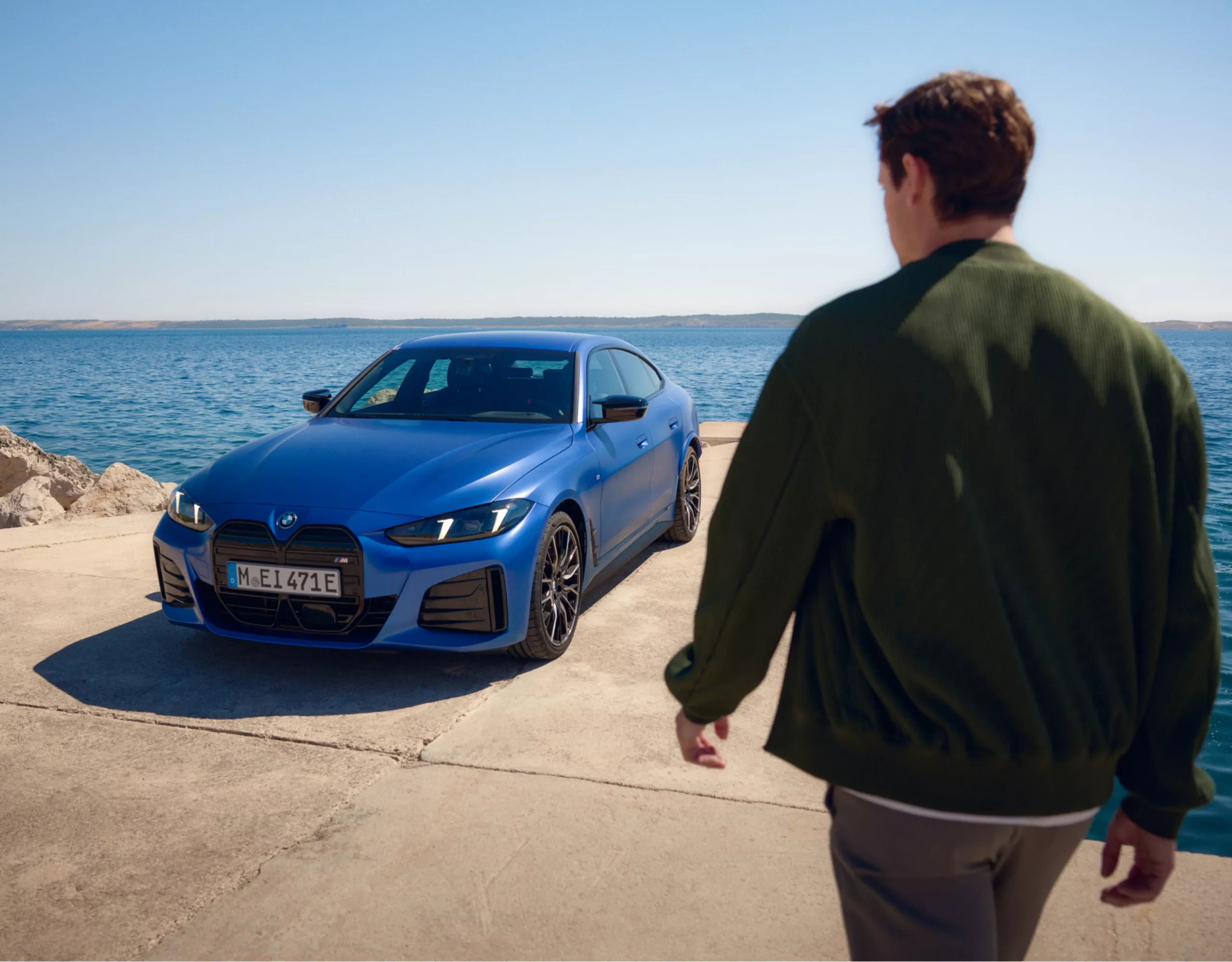 Person geht auf am Meer geparkten BMW zu