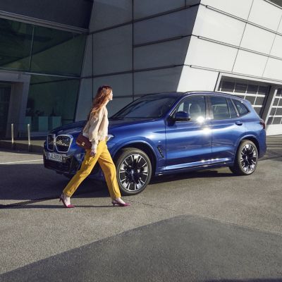 Une personne passe devant une BMW garée devant le bâtiment