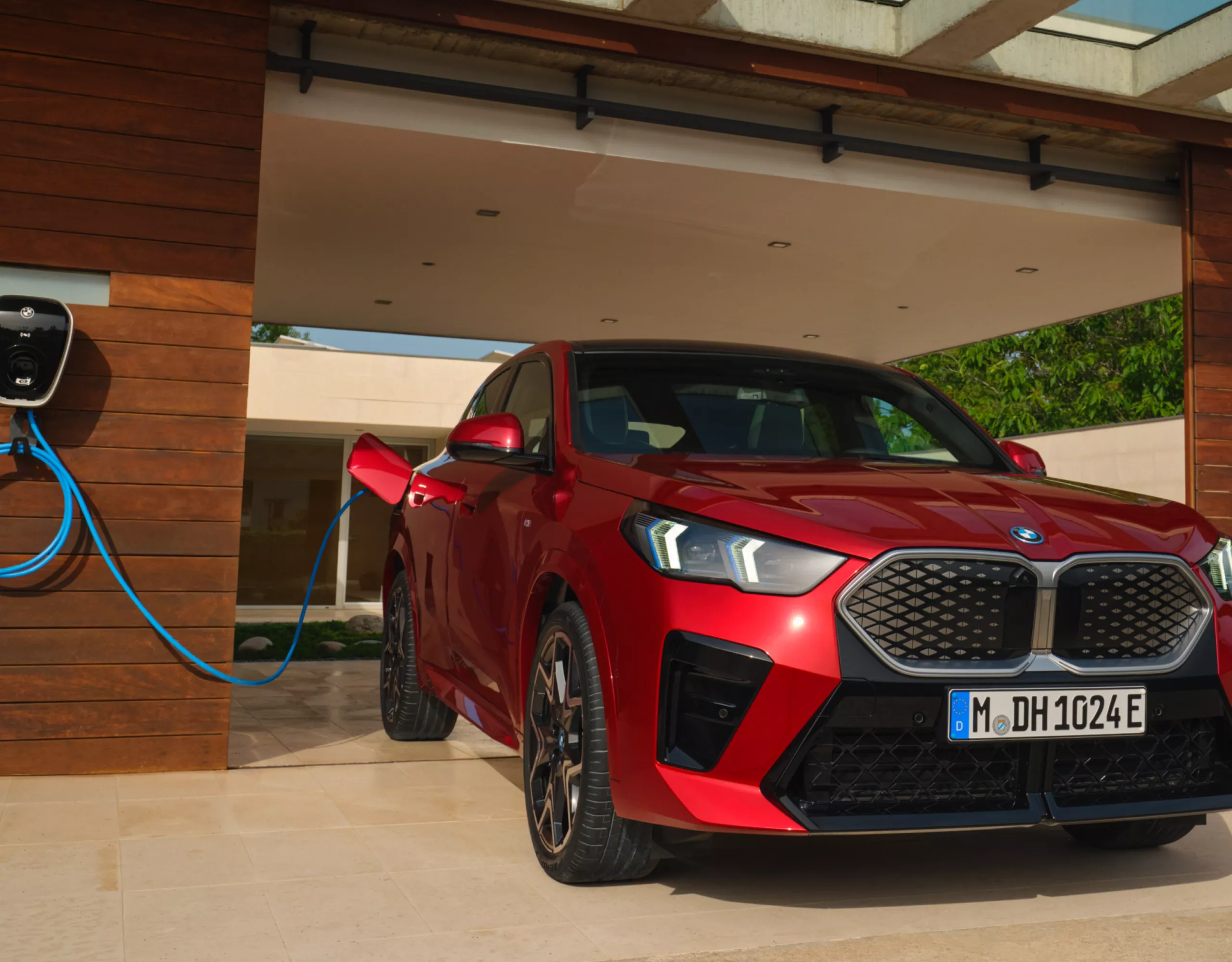 Ein roter BMW lädt an einer Ladestation in einer Garage aus Holz