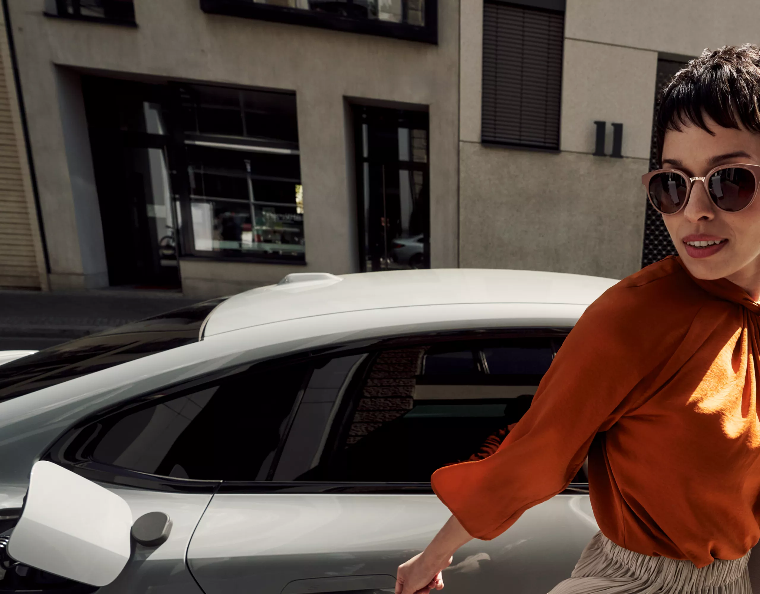 Woman in front of a BMW with an open charging flap