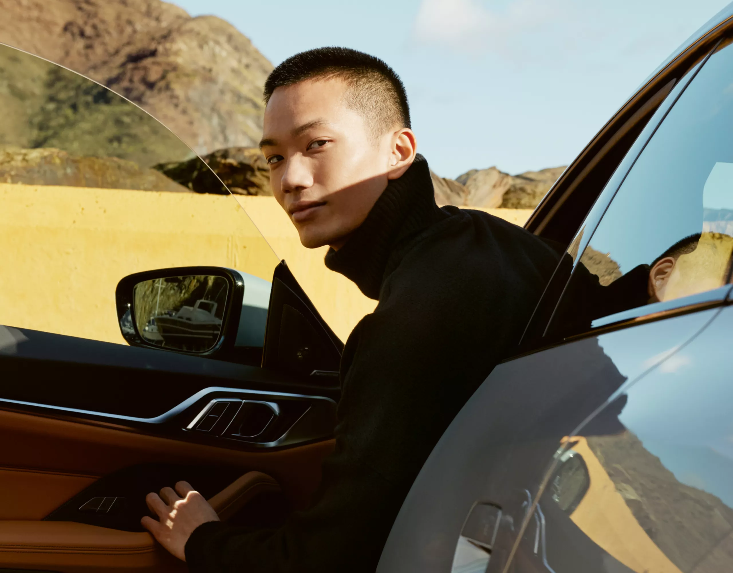 Ein junger Mann lehnt sich aus dem Fahrersitz eines geparkten Autos mit geöffneter Tür