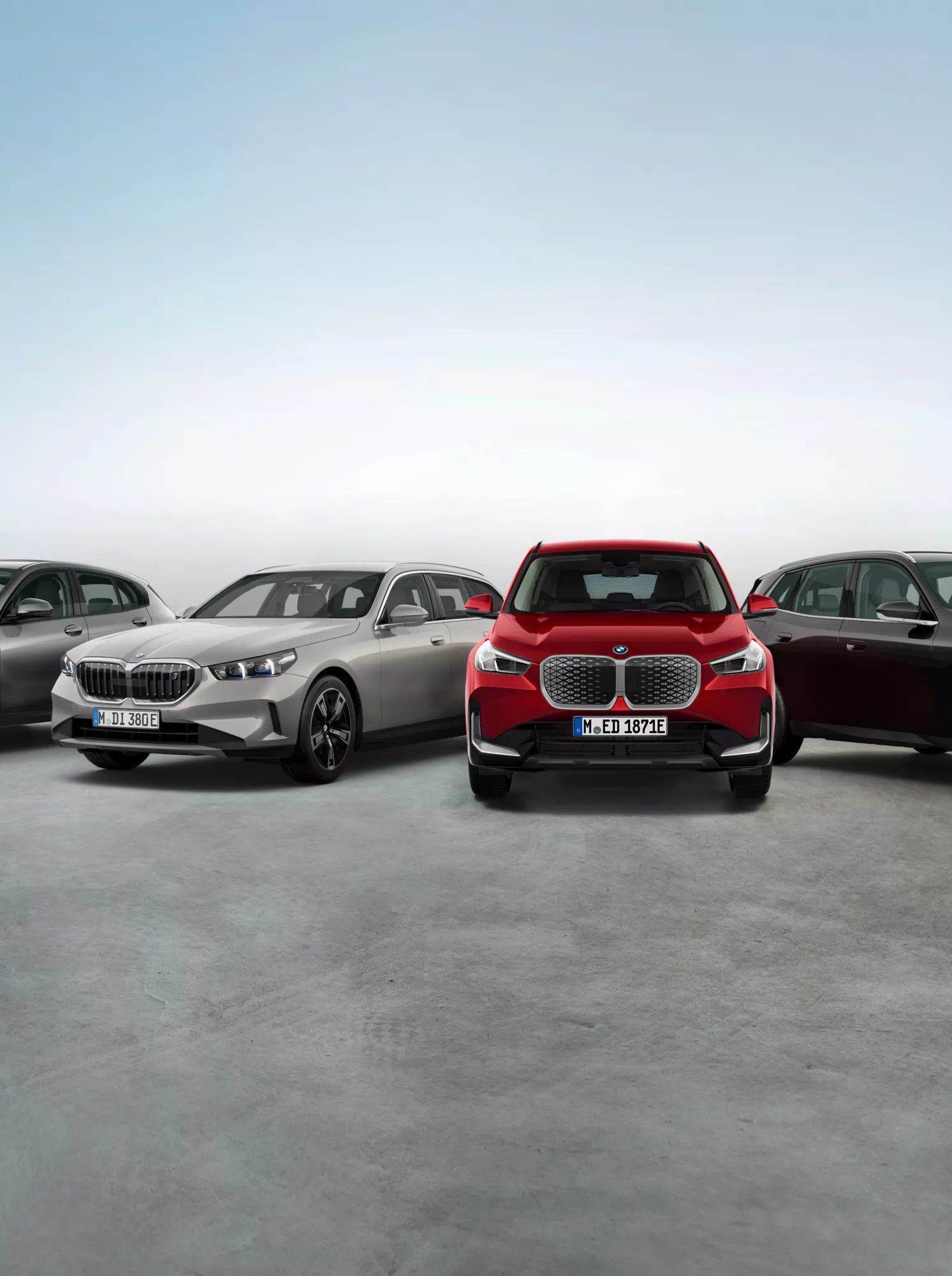Mehrere BMW Fahrzeuge stehen nebeneinander vor hellem Hintergrund.