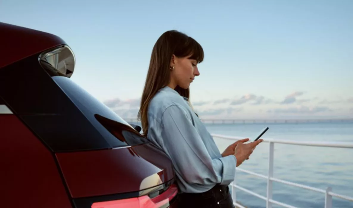 Woman checking mobile phone while leaning on BMW iX