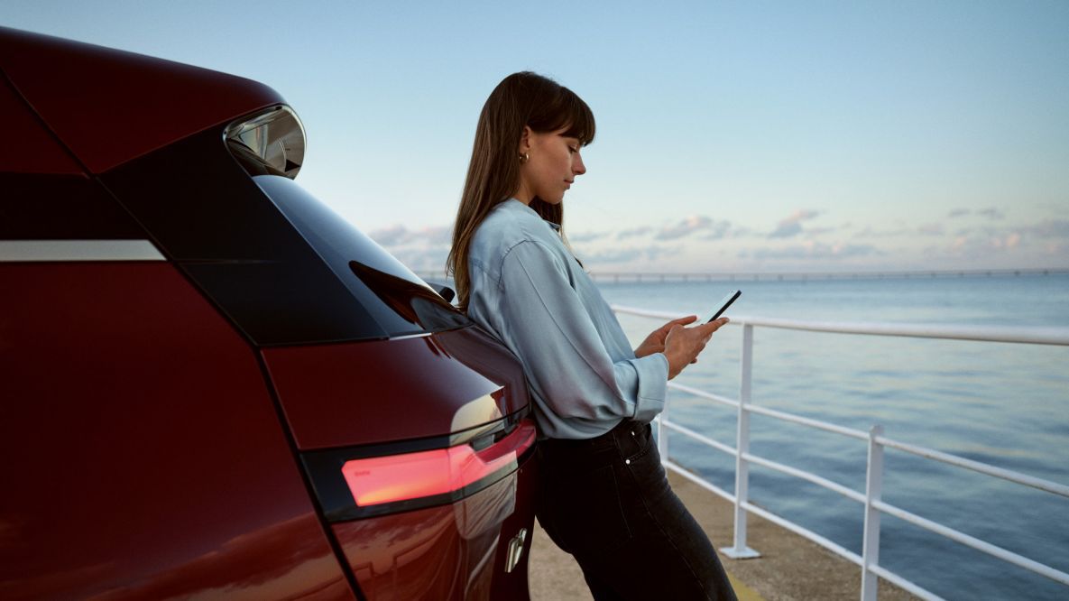 Woman checking mobile phone while leaning on BMW iX