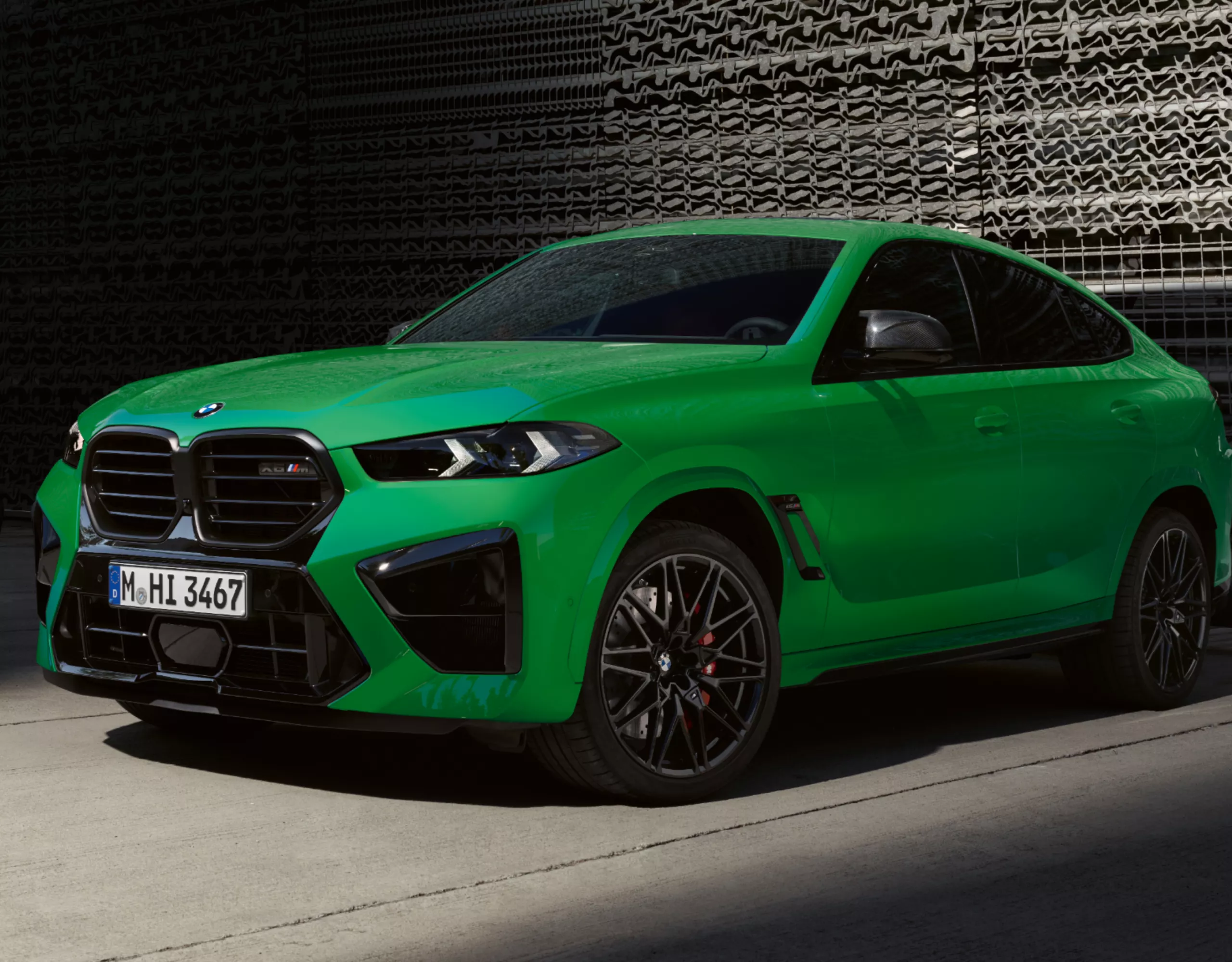BMW X6 M parkt vor Gitterwand