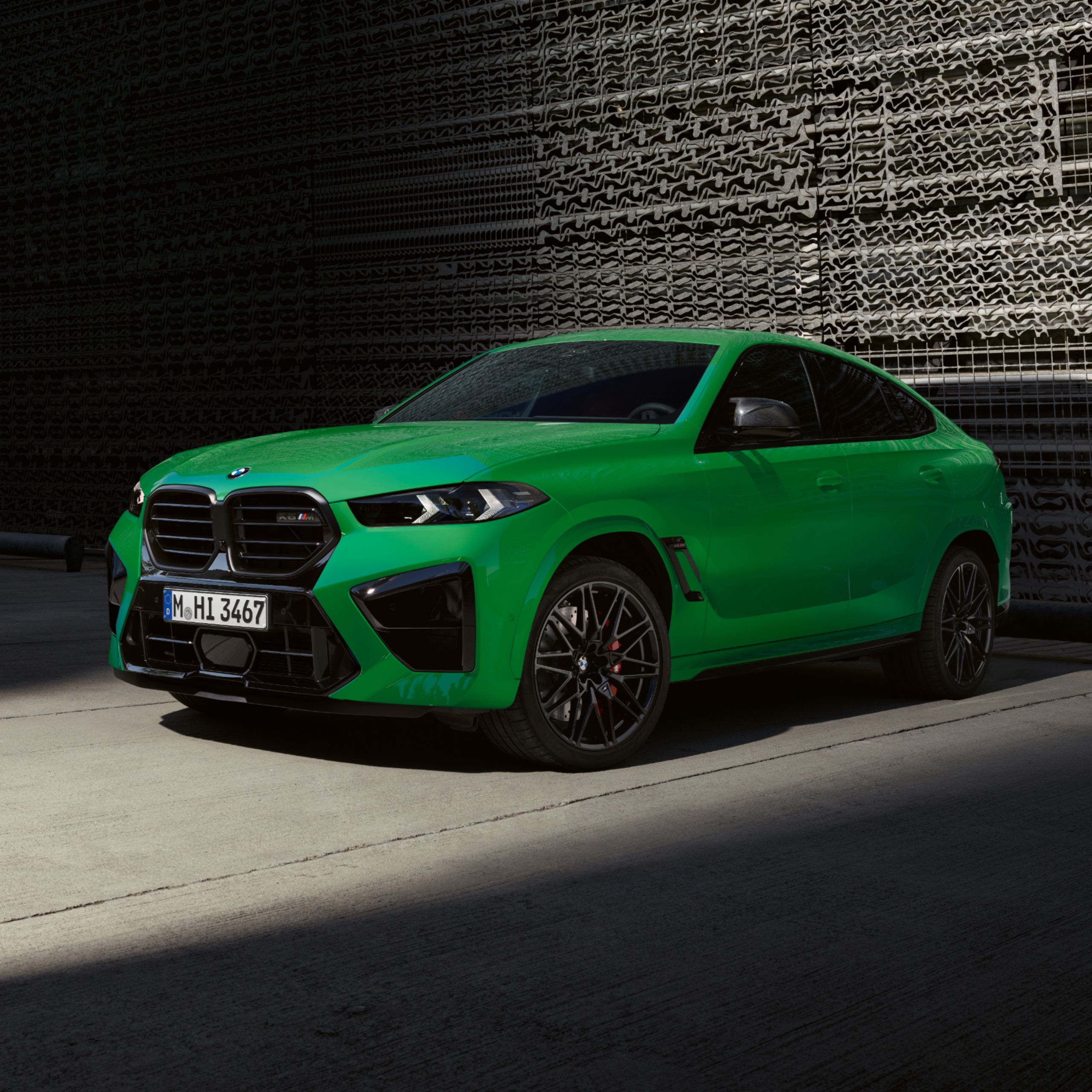 De BMW X6 M staat geparkeerd voor een traliewand