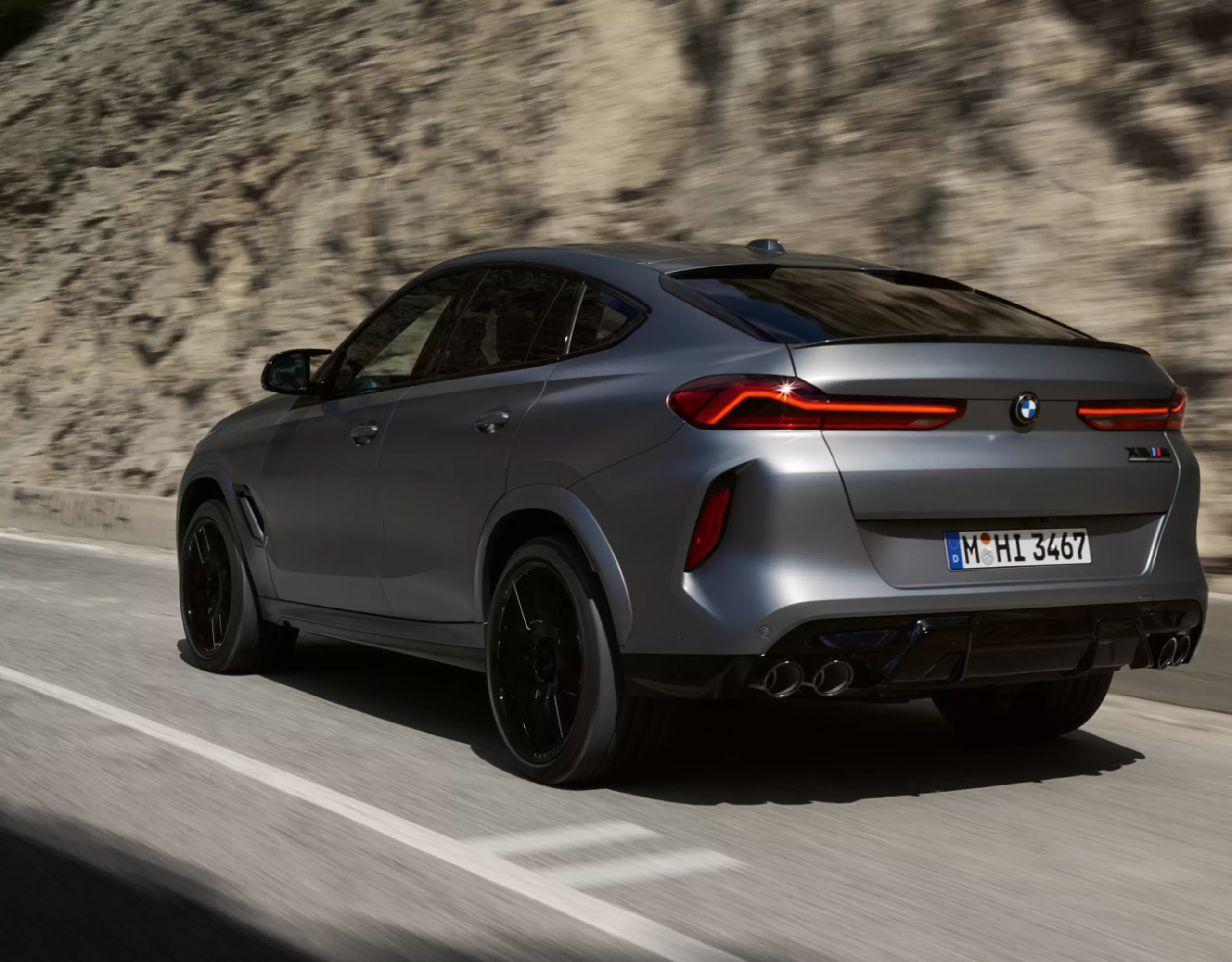 BMW X6 M Competition fährt auf Landstraße durch ein Tal