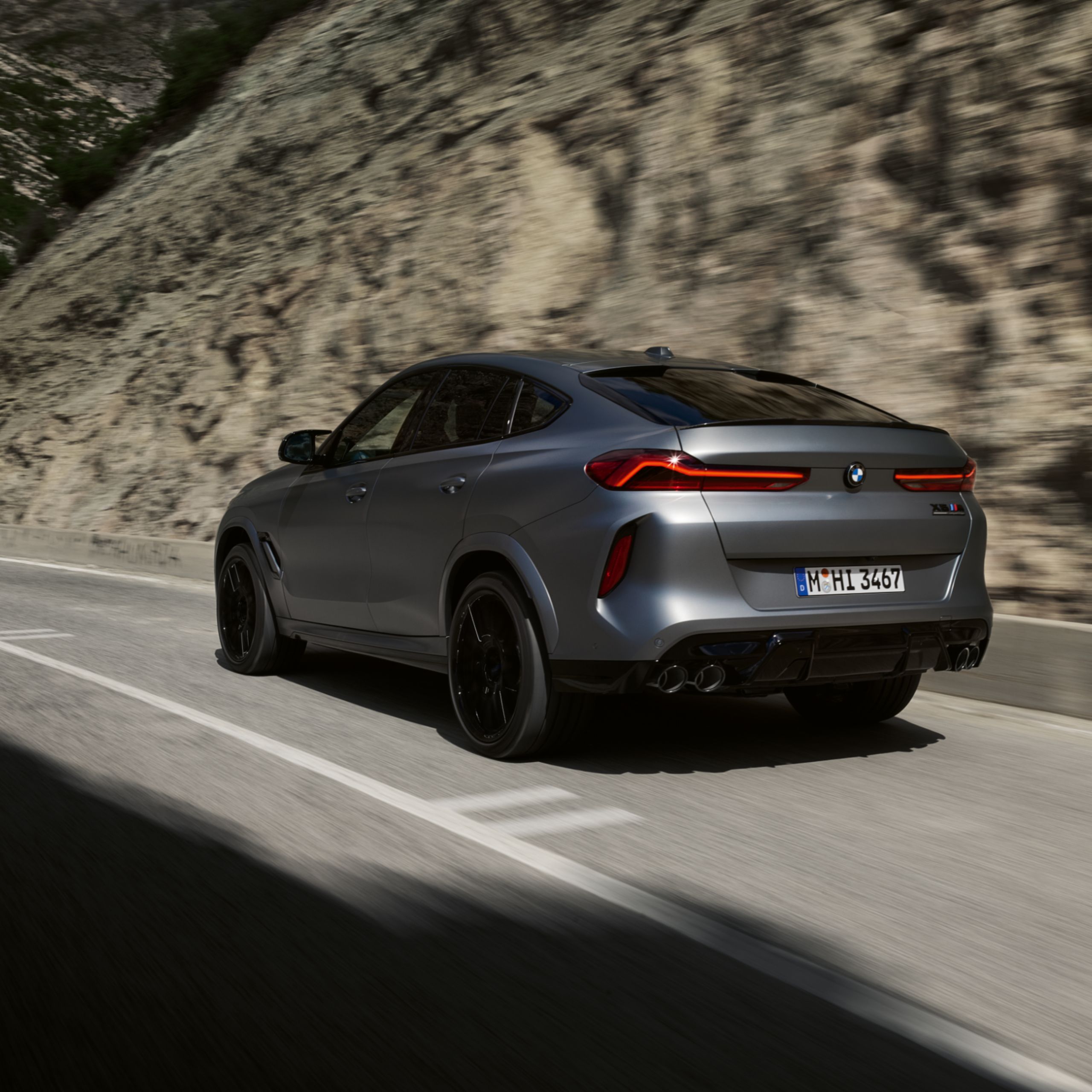 BMW X6 M Competition rijdt door een vallei op een landweg