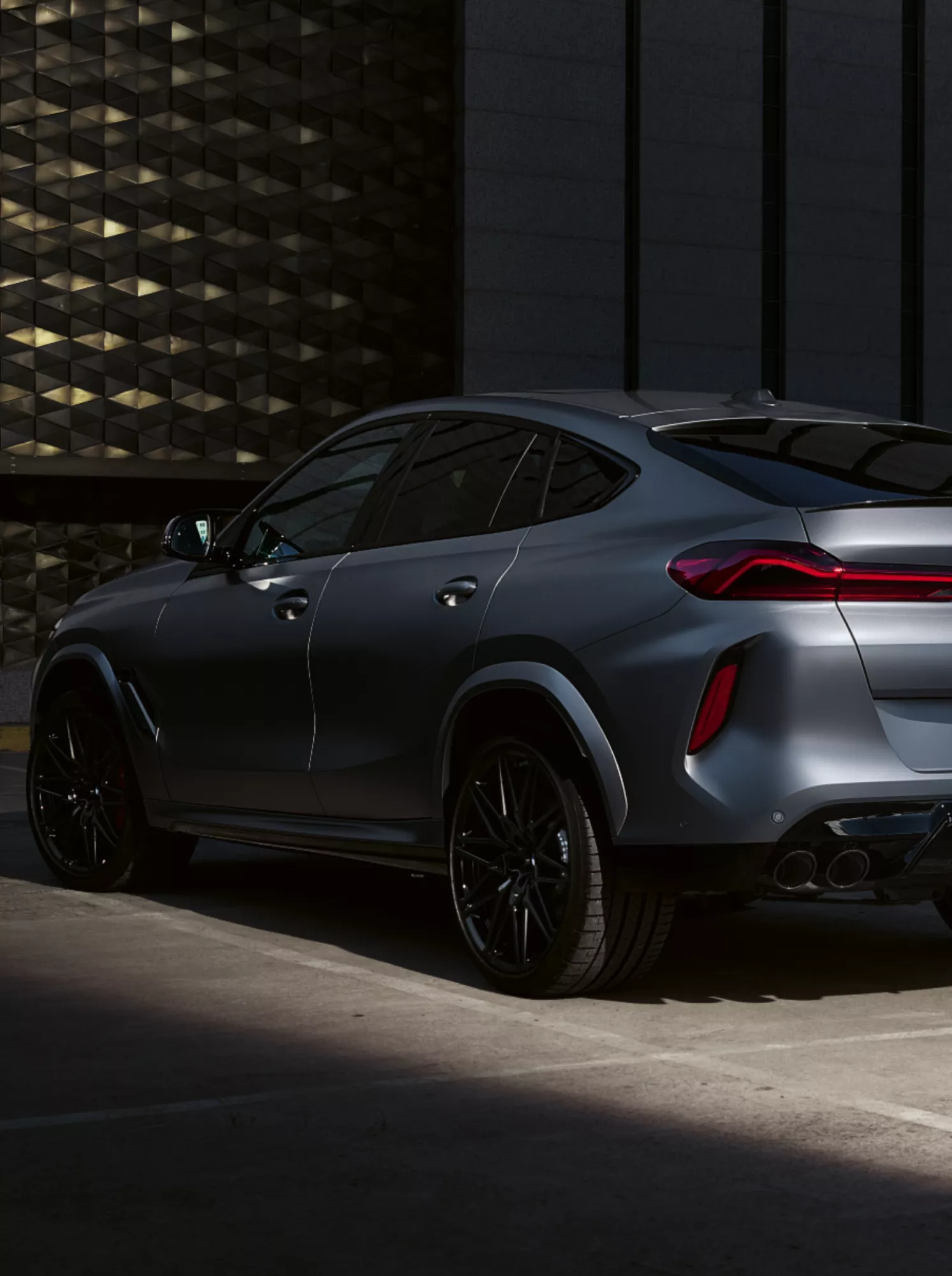 Mensch im Schatten vor im Halbschatten parkendem BMW X6
