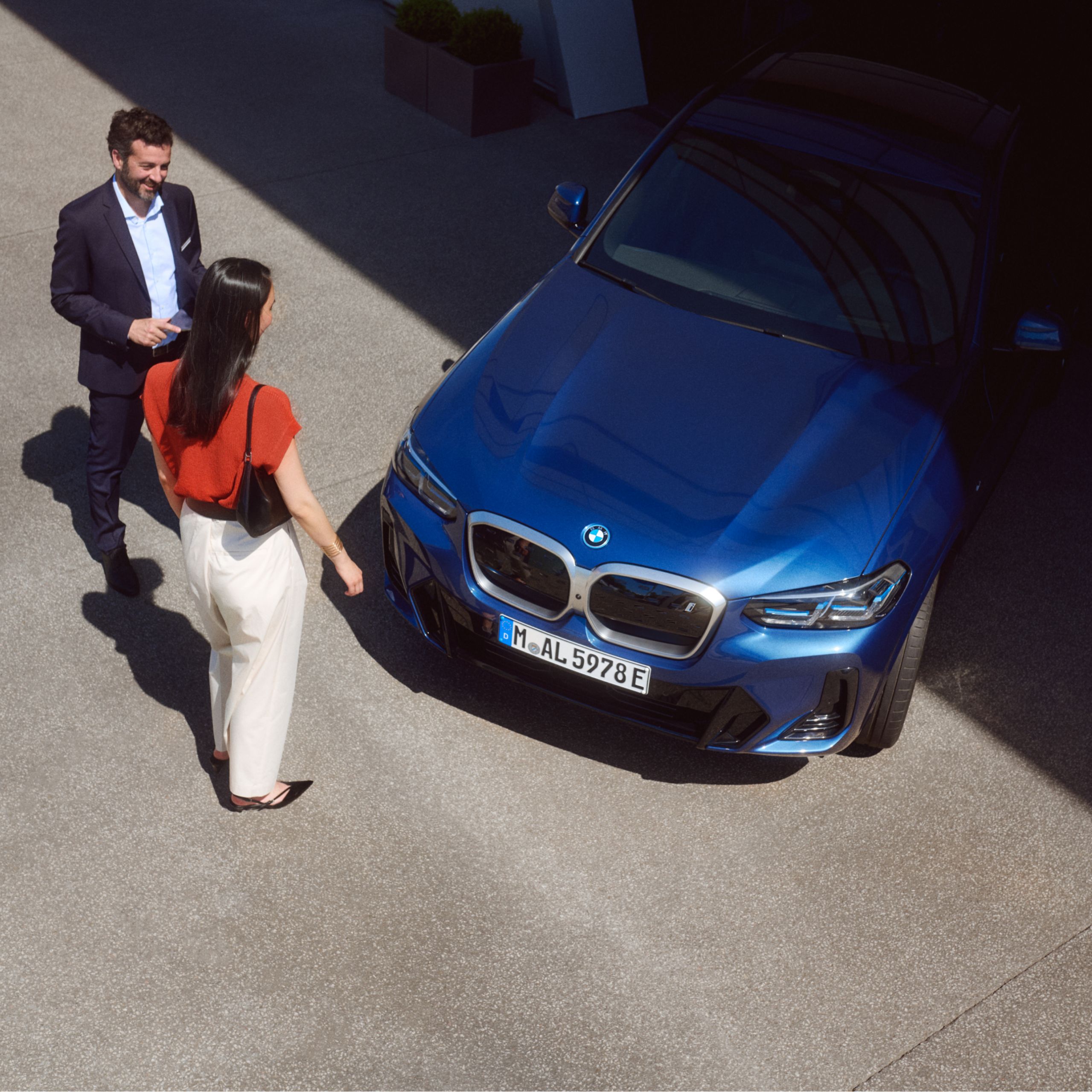 Muž a žena stoja pred BMW