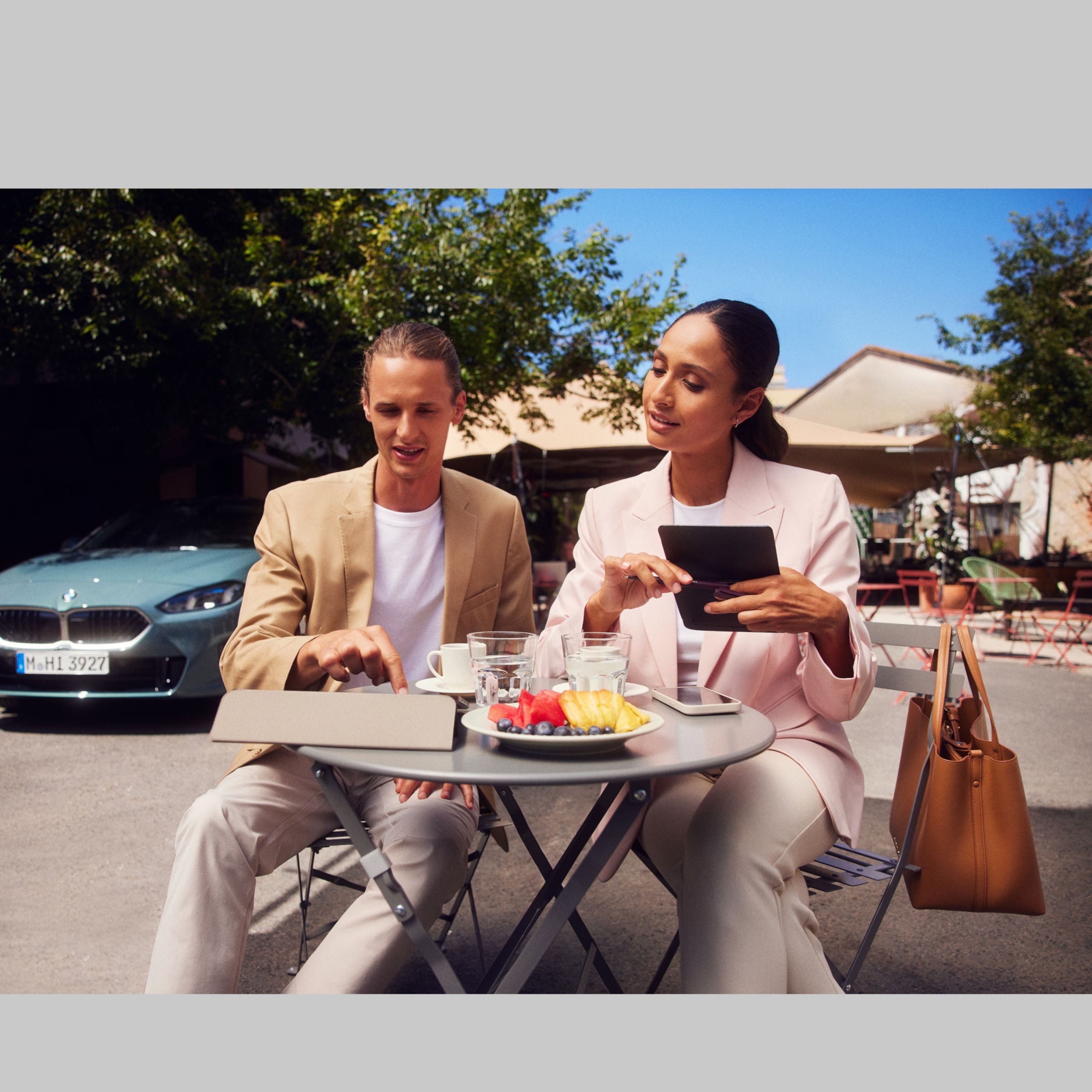 Muž sedí pri stole a ťuká na tablet. Žena vedľa neho sa naň tiež pozerá