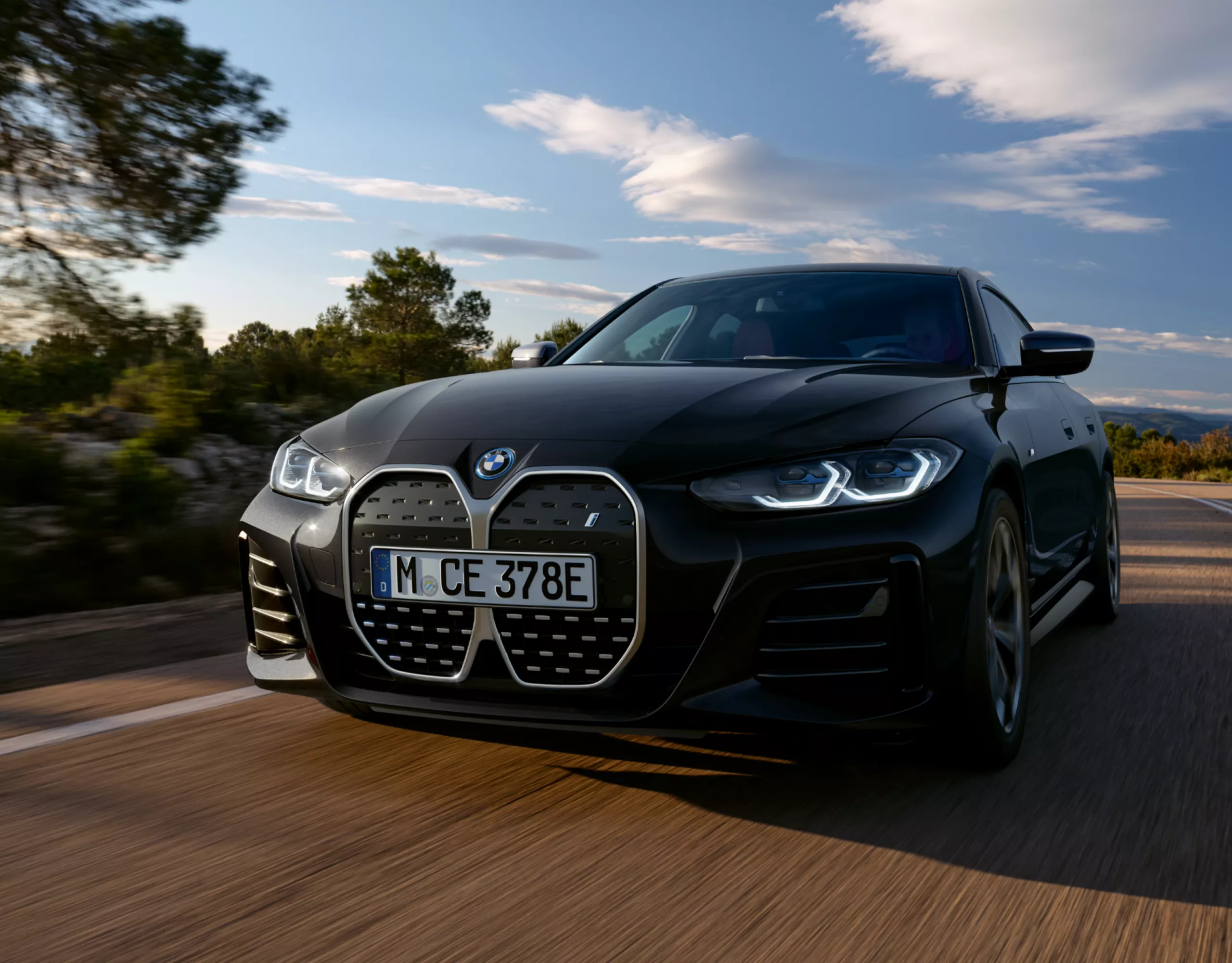 Ein BMW i4 fährt auf einer Strecke, umgeben von Natur und blauem Himmel