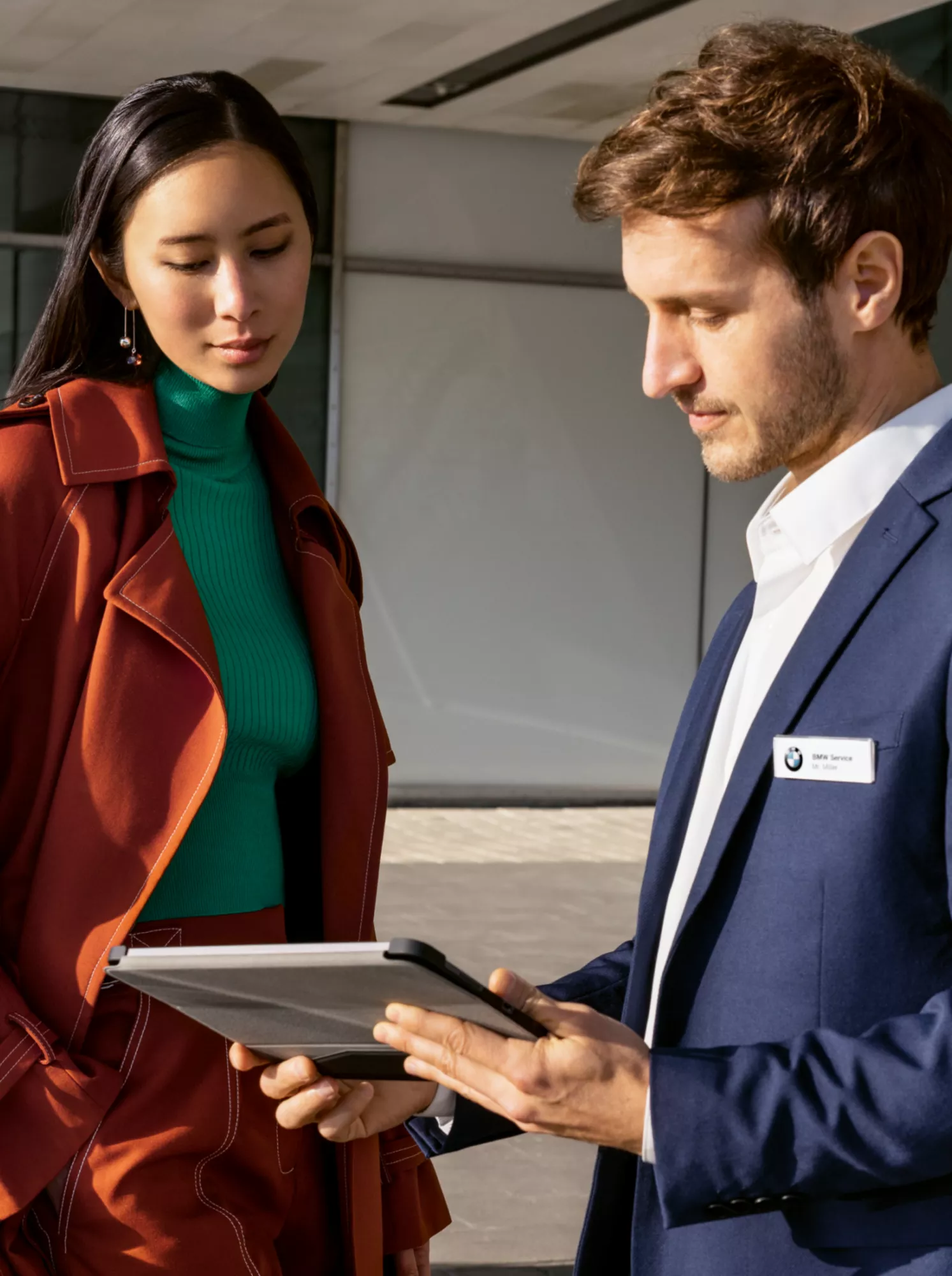 Un vendeur en concession BMW présente à une cliente sur une tablette les différents produits de financement