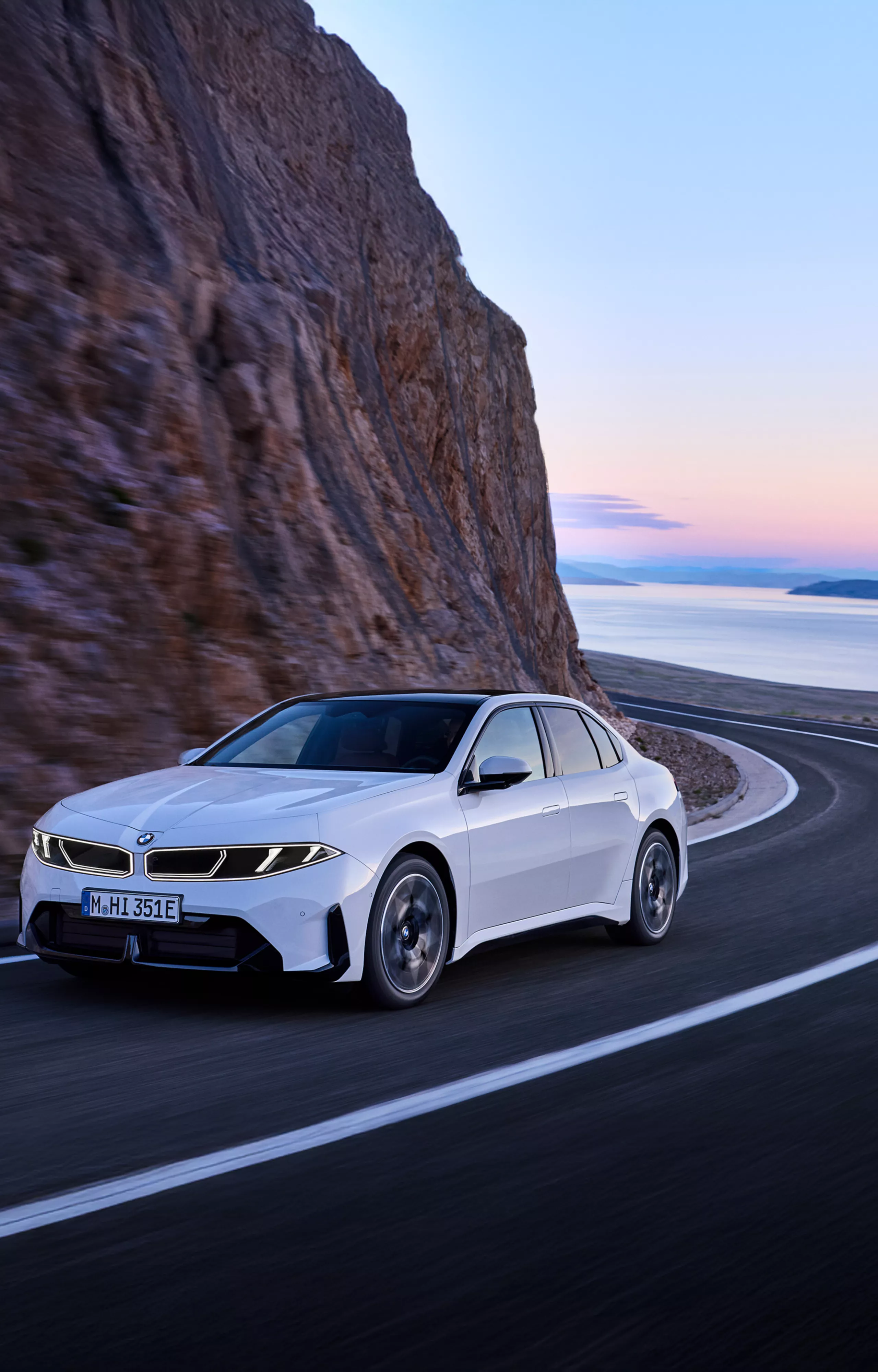  BMW i3 50 xDrive First Edition fährt auf einer Küstenstraße und zeigt sein modernes Design und seine rein elektrische Leistung.