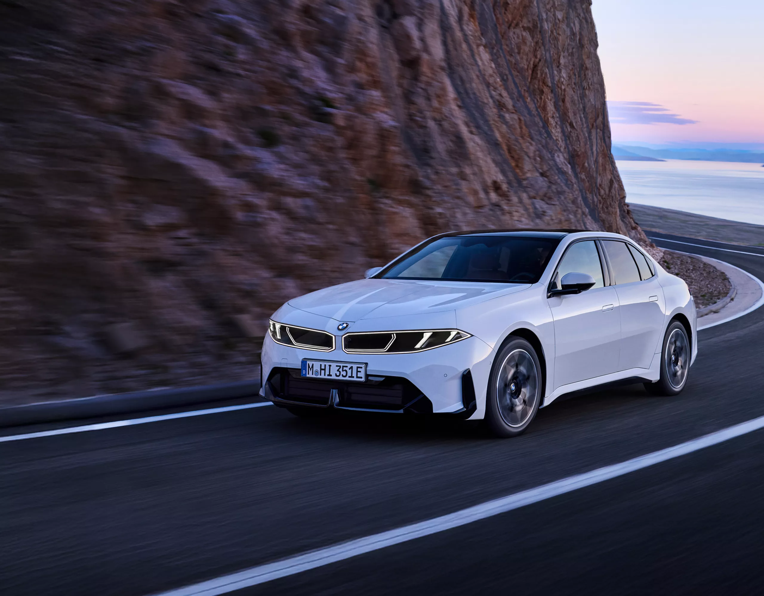A BMW i3 Saloon is driving on a curvy serpentine road through the mountains
