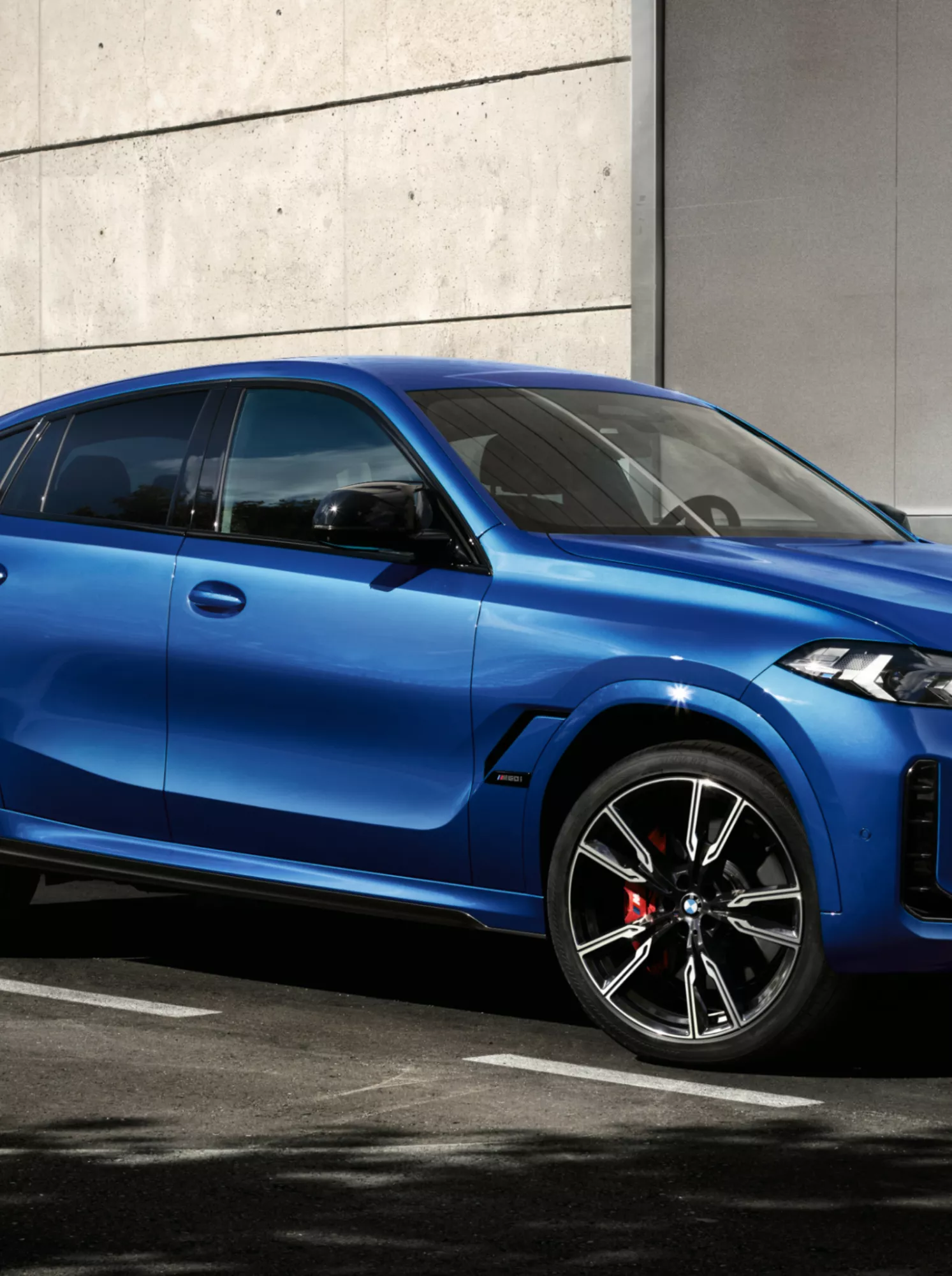 Ein Mann nähert sich einem BMW X6, der vor einem modernen Gebäude geparkt ist