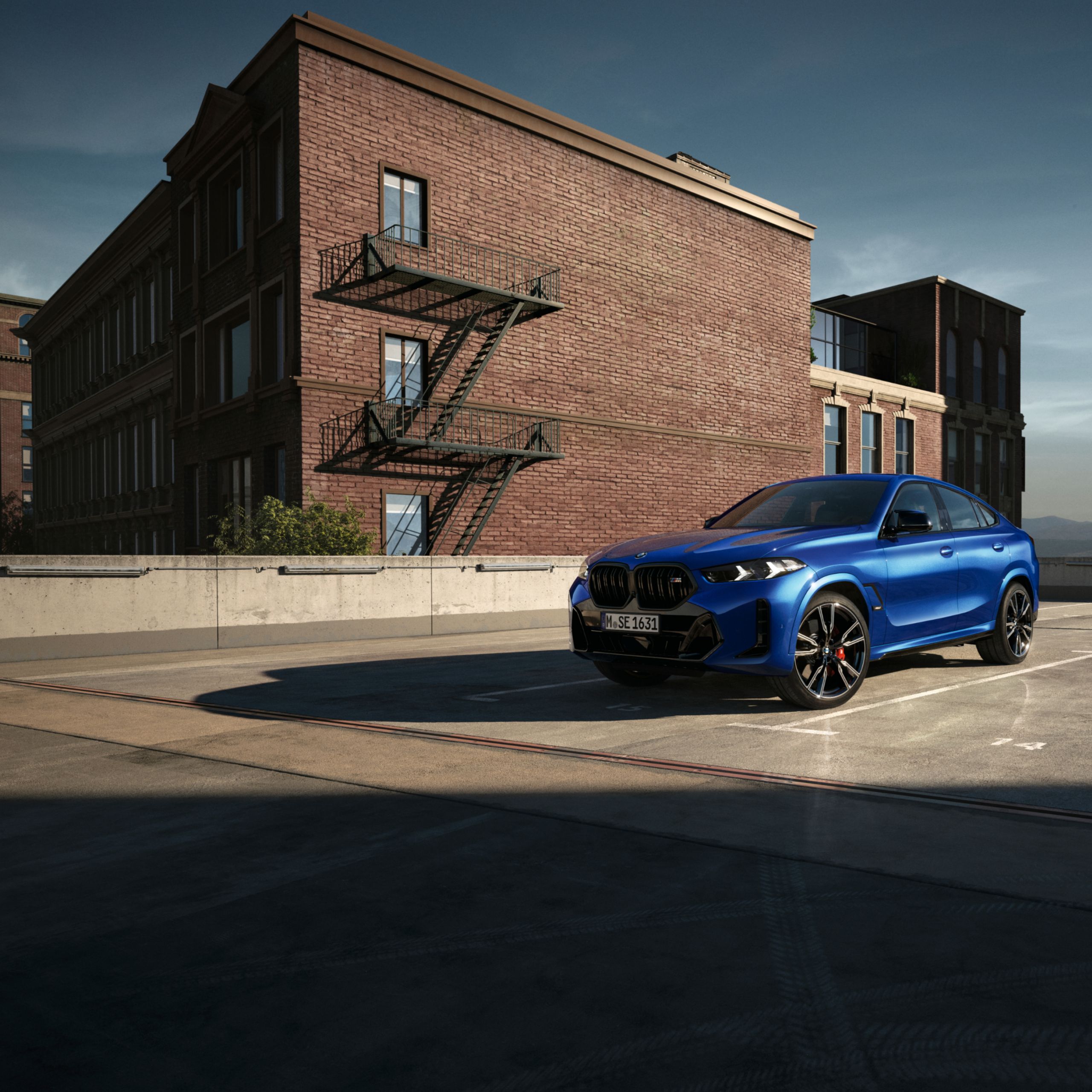Een BMW X6 SUV staat in het zonlicht op een parkeerplaats voor een bakstenen gebouw