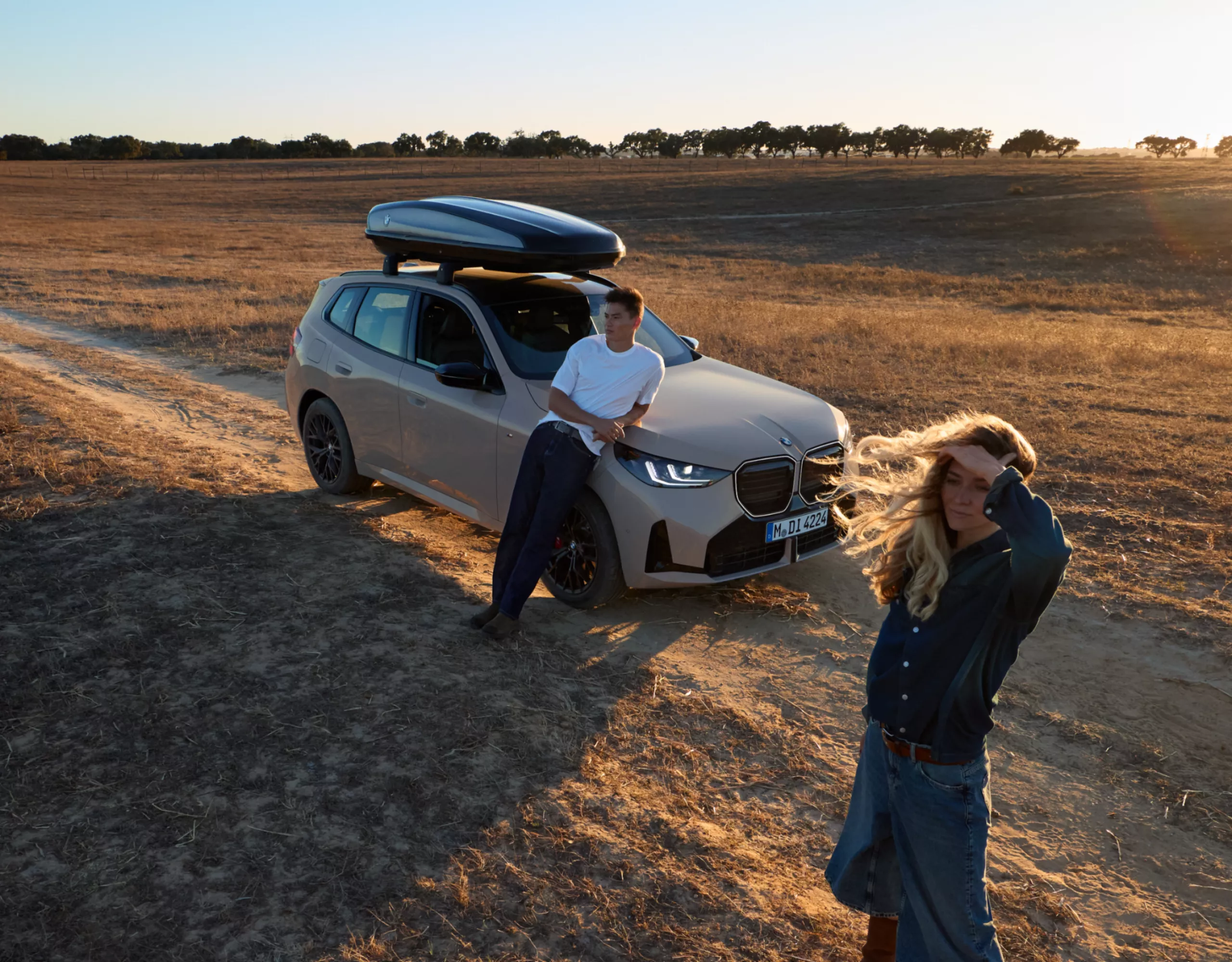 Eine Frau und ein Mann stehen vor einem BMW auf freiem Feld, der mit Original BMW Zubehör ausgestattet ist