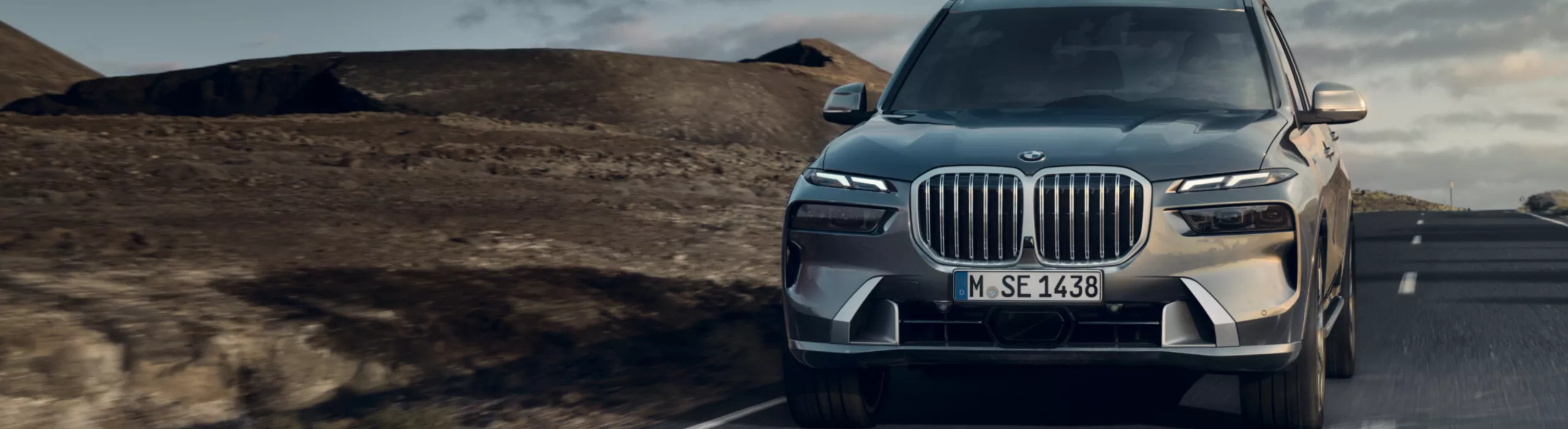 Een BMW X7 rijdt over een weg door een hamada-woestijnlandschap