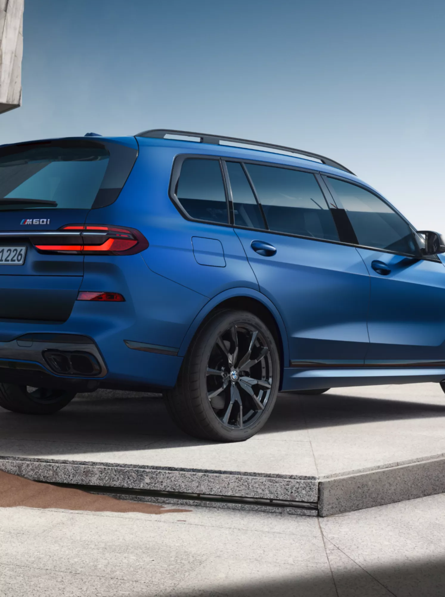 Une BMW X7 M60i xDrive est garée devant un bâtiment futuriste