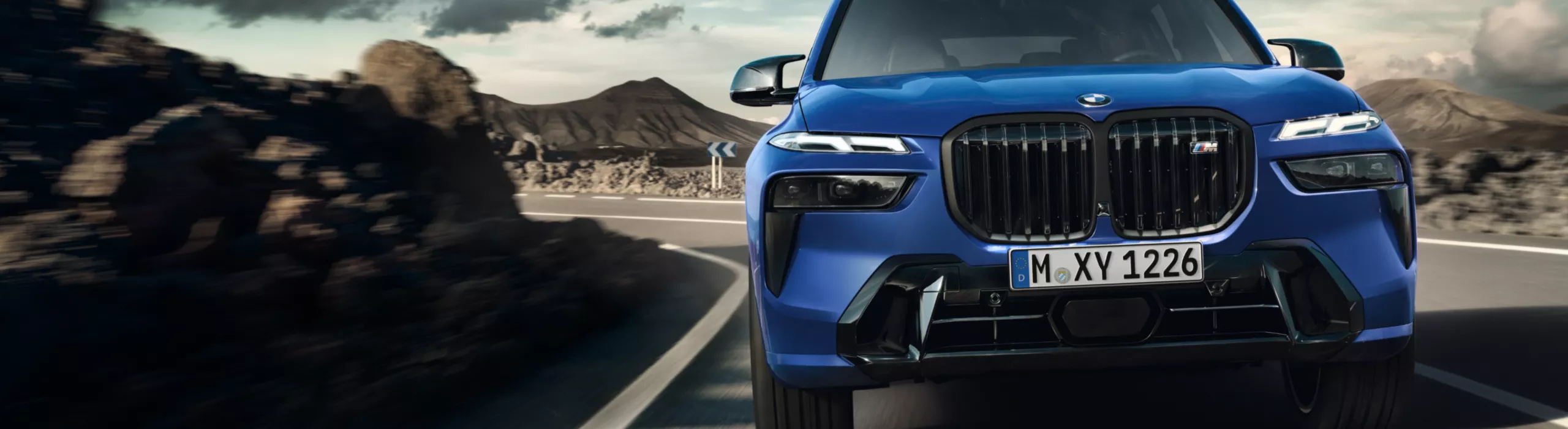 Ein BMW X7 M60i xDrive steht auf einem Steinplateau unter blauem Himmel