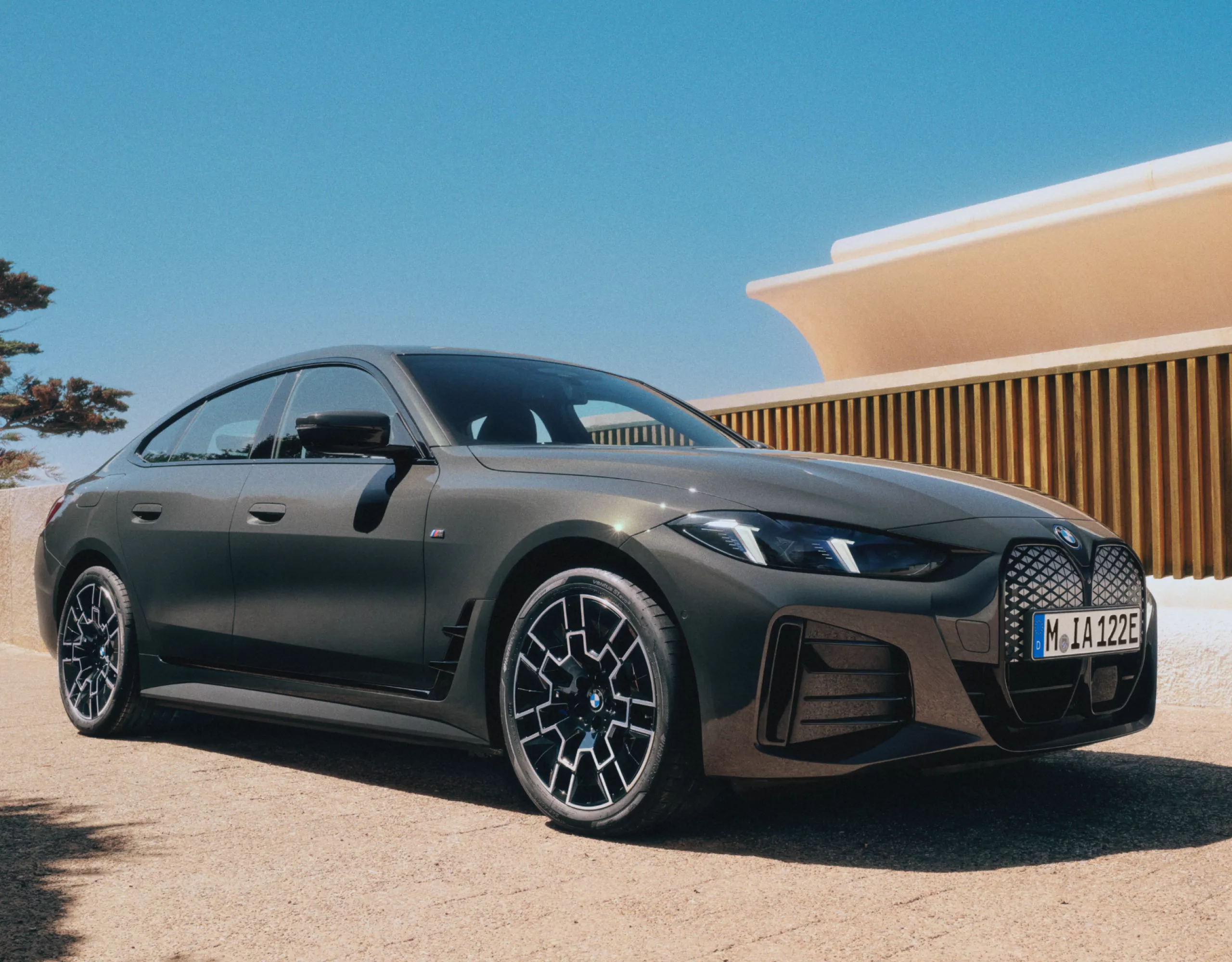 BMW i4，純電轎跑，Tansanite Blue Metallic銀粉漆，在陽光明媚的山邊小湖旁的道路上