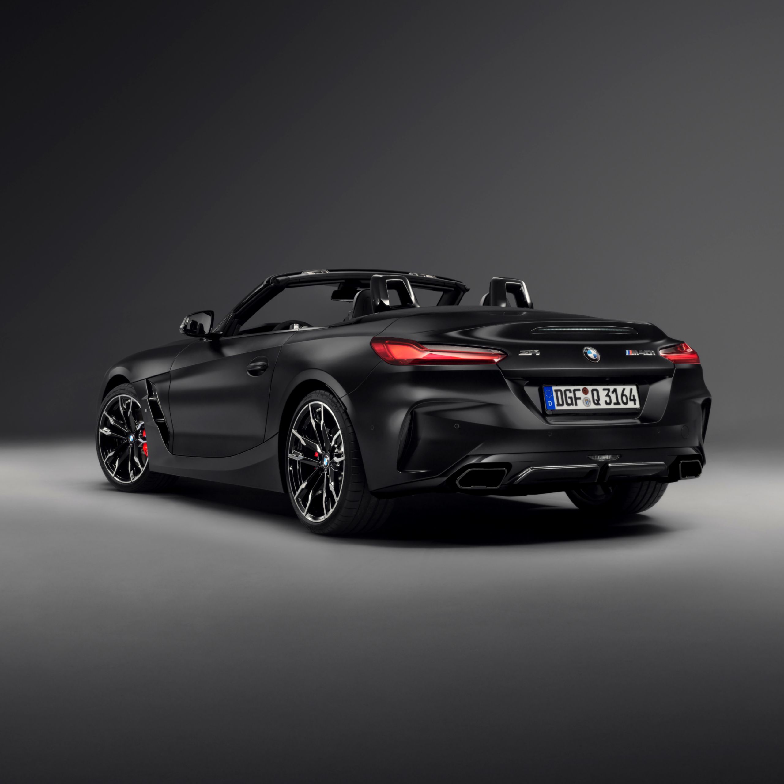 Heckansicht des BMW Z4 M40i Roadster Final Edition mit offenem Verdeck, BMW Individual Frozen Black metallic Lackierung und schwarzen Endrohren