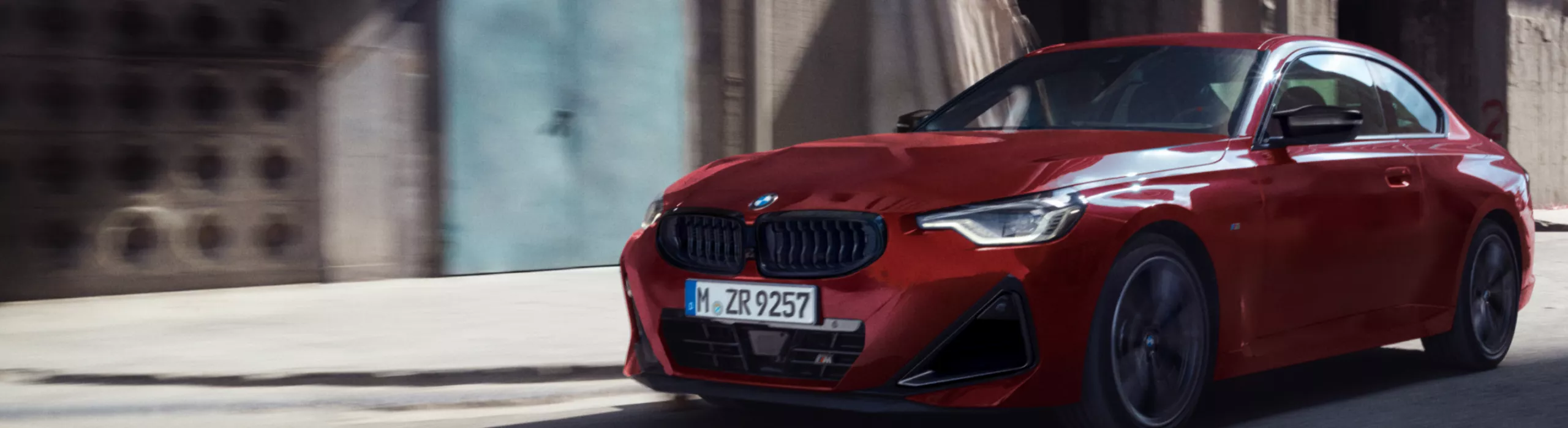 Ein BMW 2er Coupé fährt auf einer Straße vor einer Baustelle