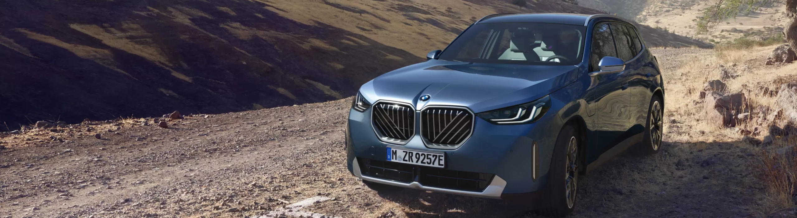 SUV BMW X3 w białym kolorze, na tle modernistycznego budynku. 