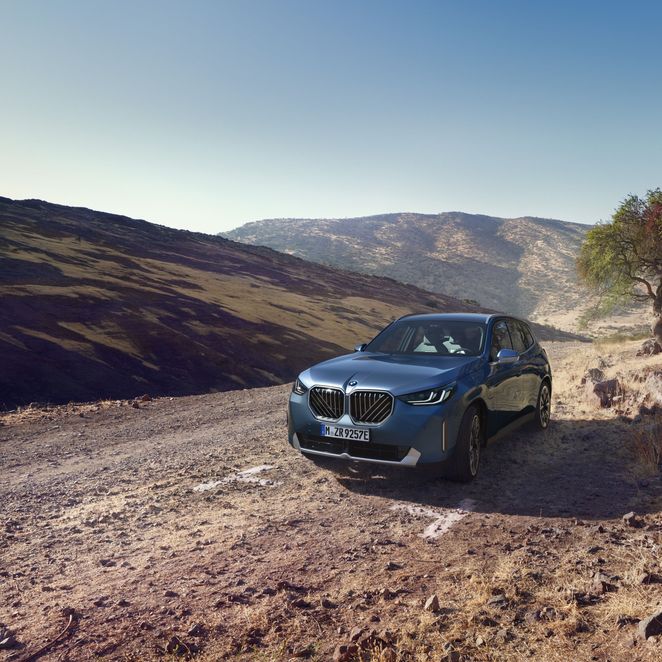 SUV BMW X3 w białym kolorze, na tle modernistycznego budynku. 