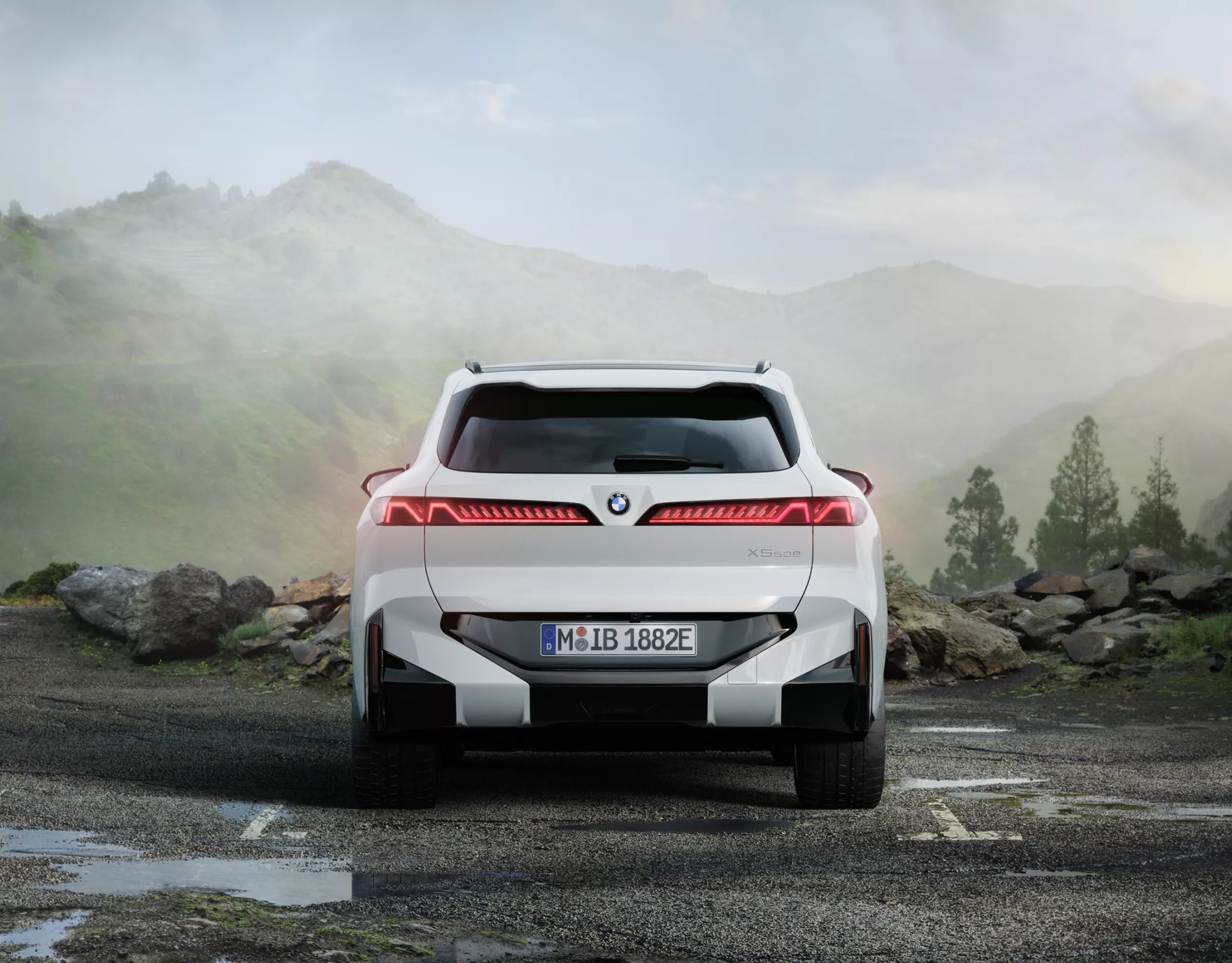BMW ir novietots pie uzlādes stacijas modernas daudzstāvu ēkas priekšā