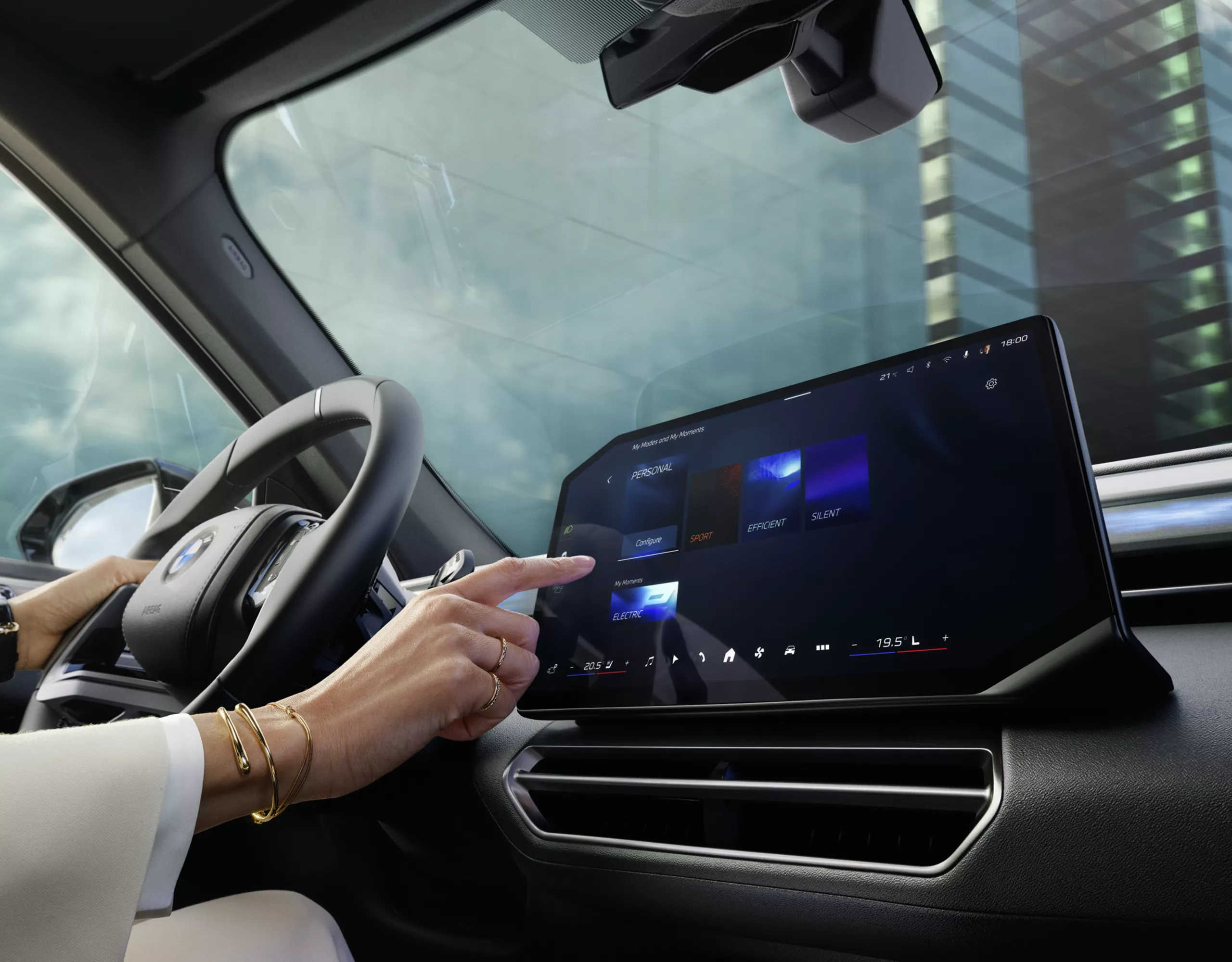 Une main effleure l'écran central d'une BMW