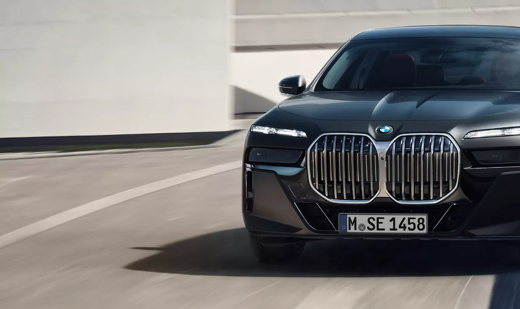 BMW 7 Series Sedan G70 ICE M sport package Frozen Deep grey metallic 3/4 front view still in front of building
