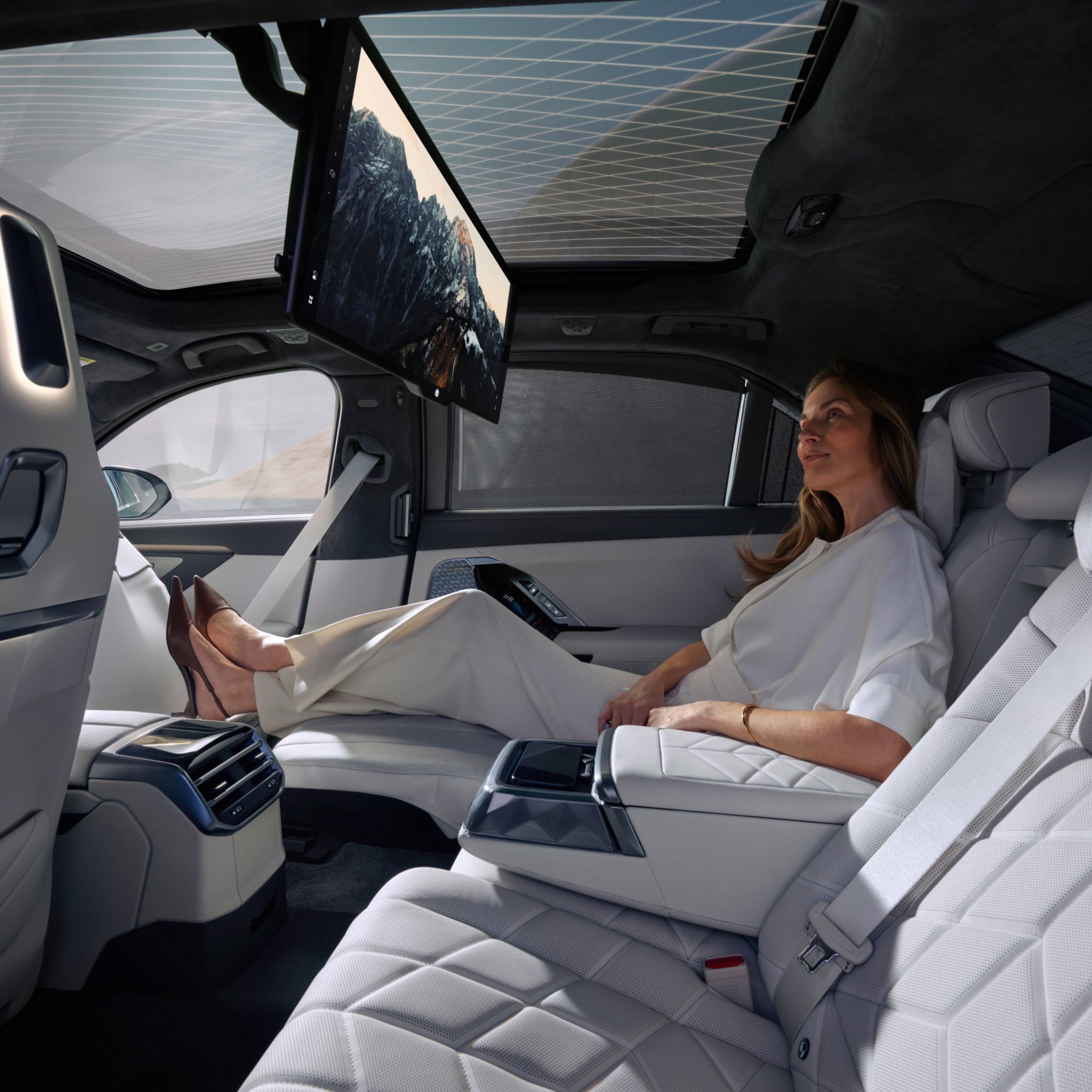 A person sits in the rear and watches a movie on the BMW Theatre Screen.