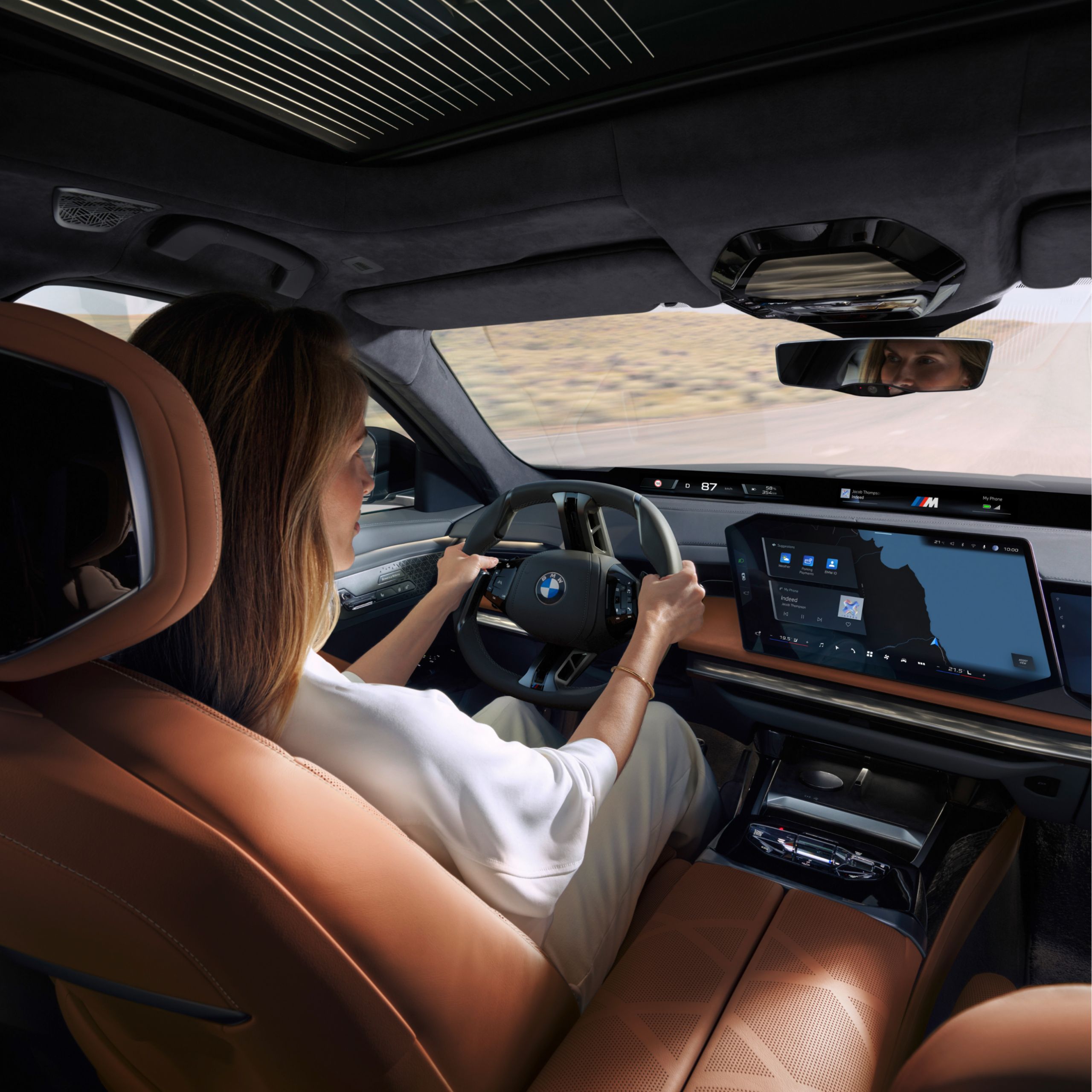 Vista dal sedile posteriore del guidatore, del volante e del display informativo centrale.