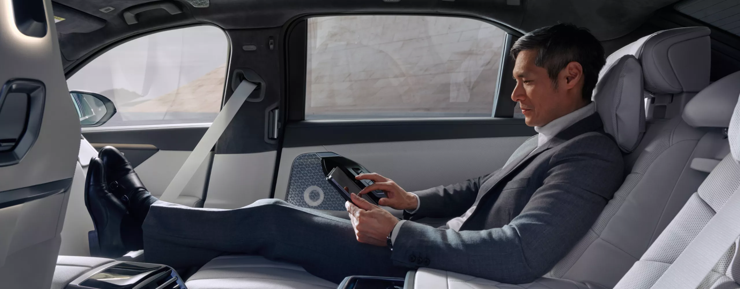 Person sitzt im Fond in der Executive Sitzposition und bedient ein Tablet.