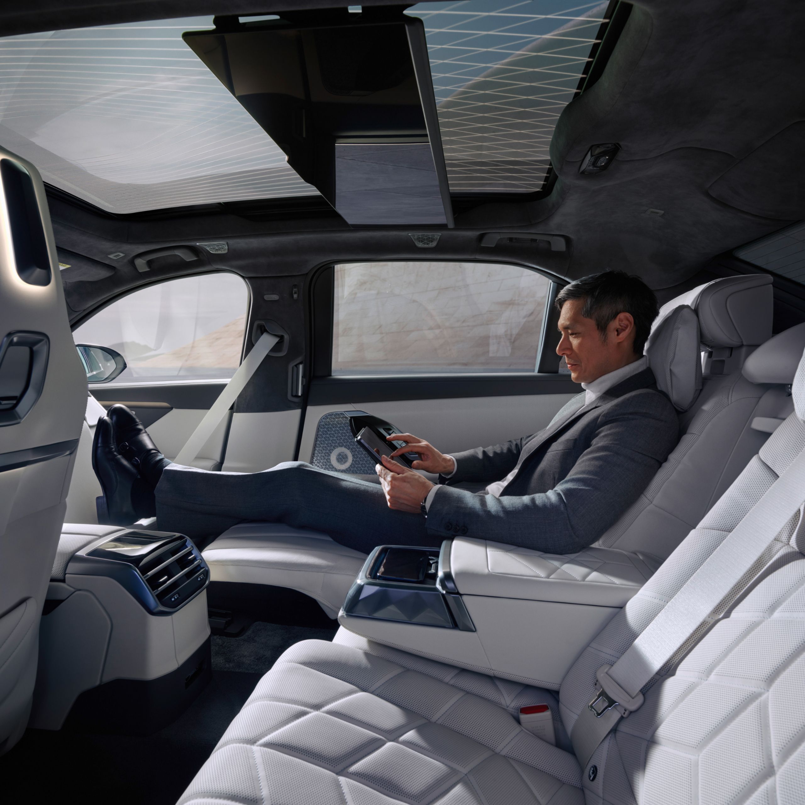 Person sitzt im Fond in der Executive Sitzposition und bedient ein Tablet.