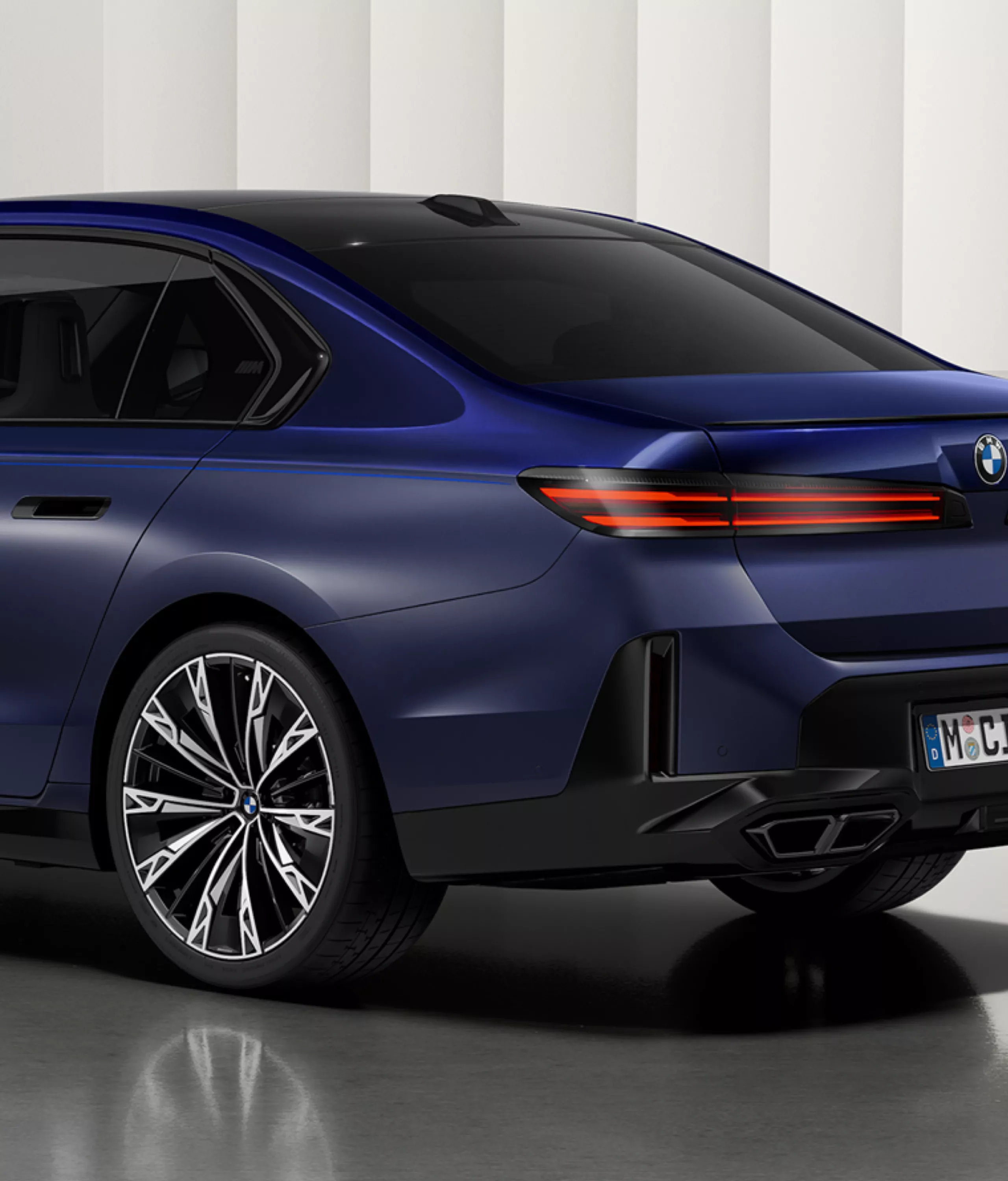 Pasviręs automobilio vaizdas iš galo ir M ženklelio ant galinio lango vaizdas iš arti