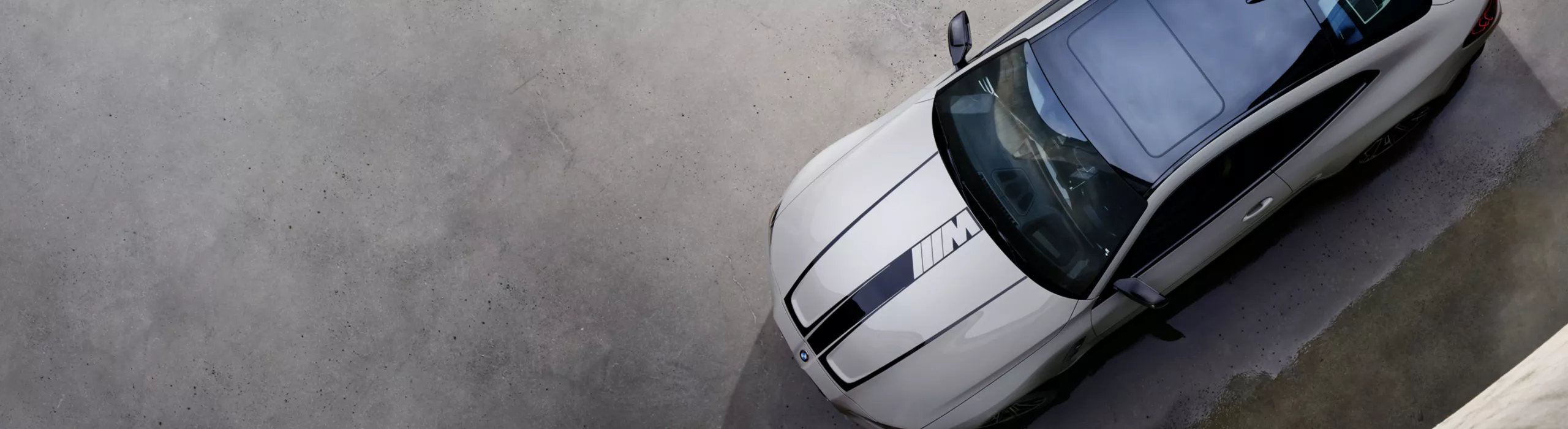 Vogelperspektive auf ein BMW M4 Coupé mit M Schriftzug auf der Motorhaube, schwarzem Zierstreifen und M Carbon Exterieurpaket