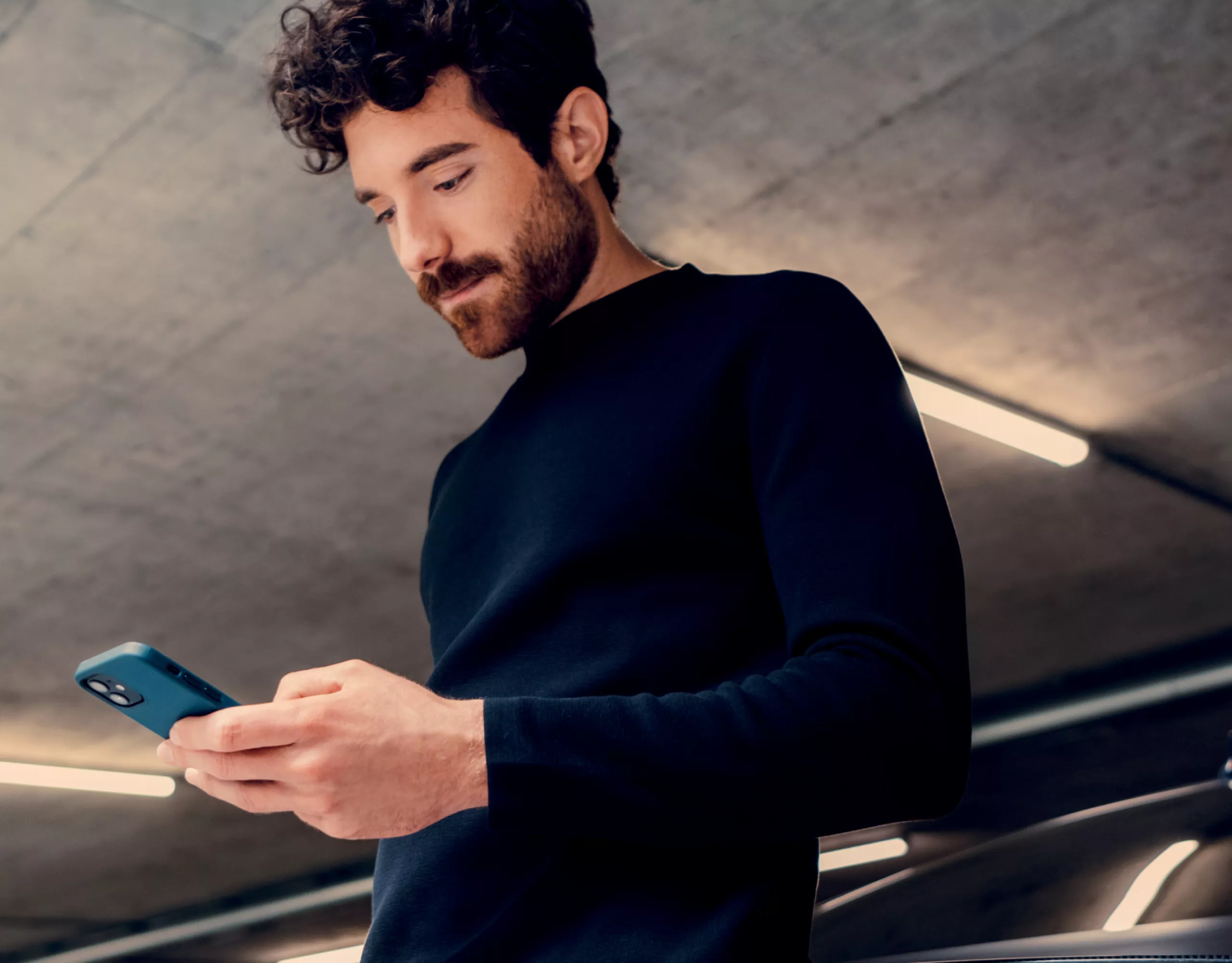Ein Mann, der sein Smartphone betrachtet, steht in einer beleuchteten Garage