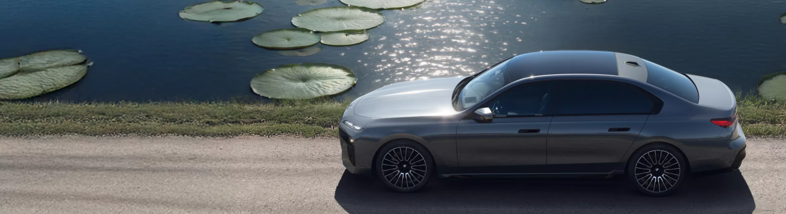 BMW i7, gökyüzünde fırtına bulutları ile çakıllı bir yolda