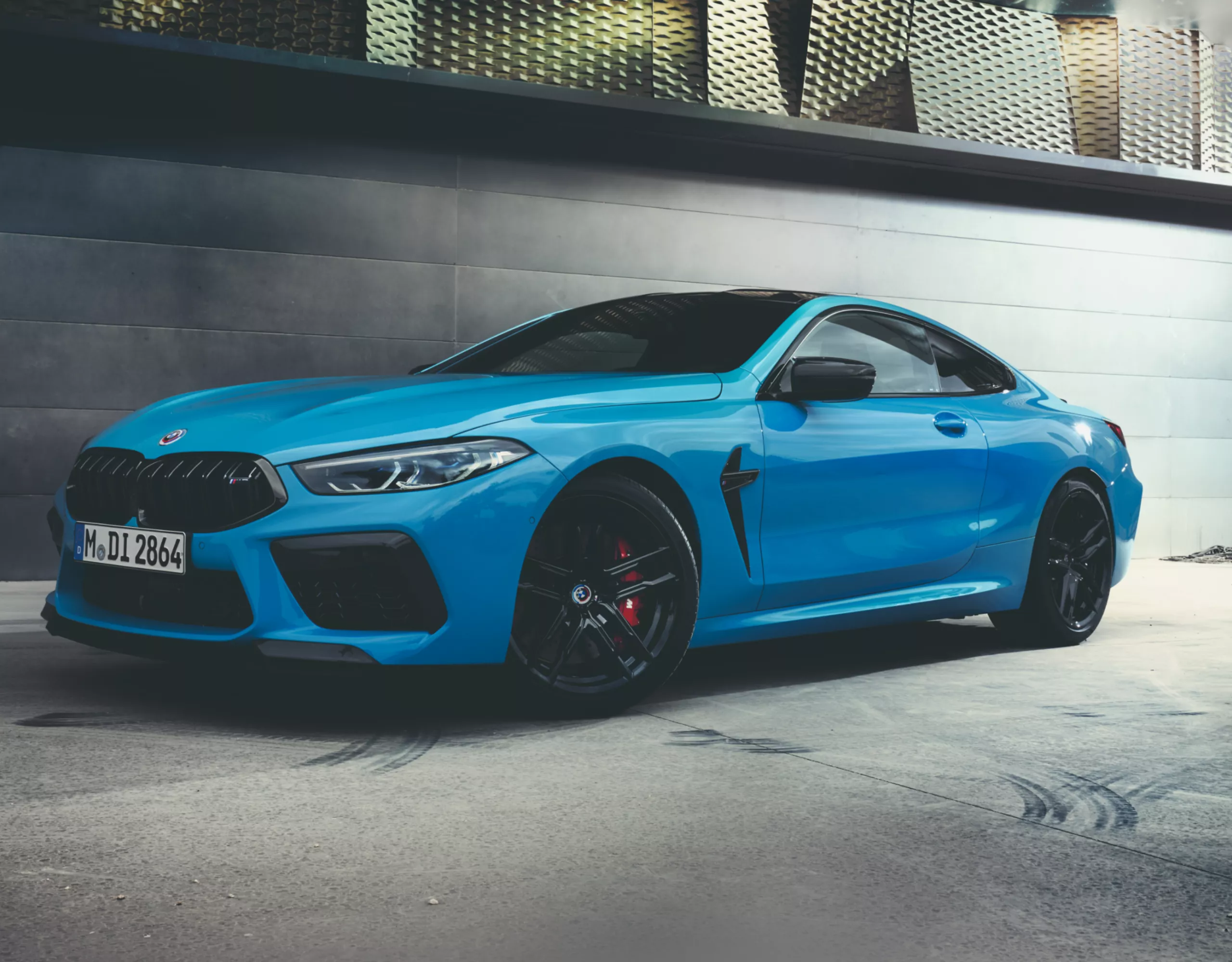 BMW M8 Competition coupé in front of a wall in a hanger