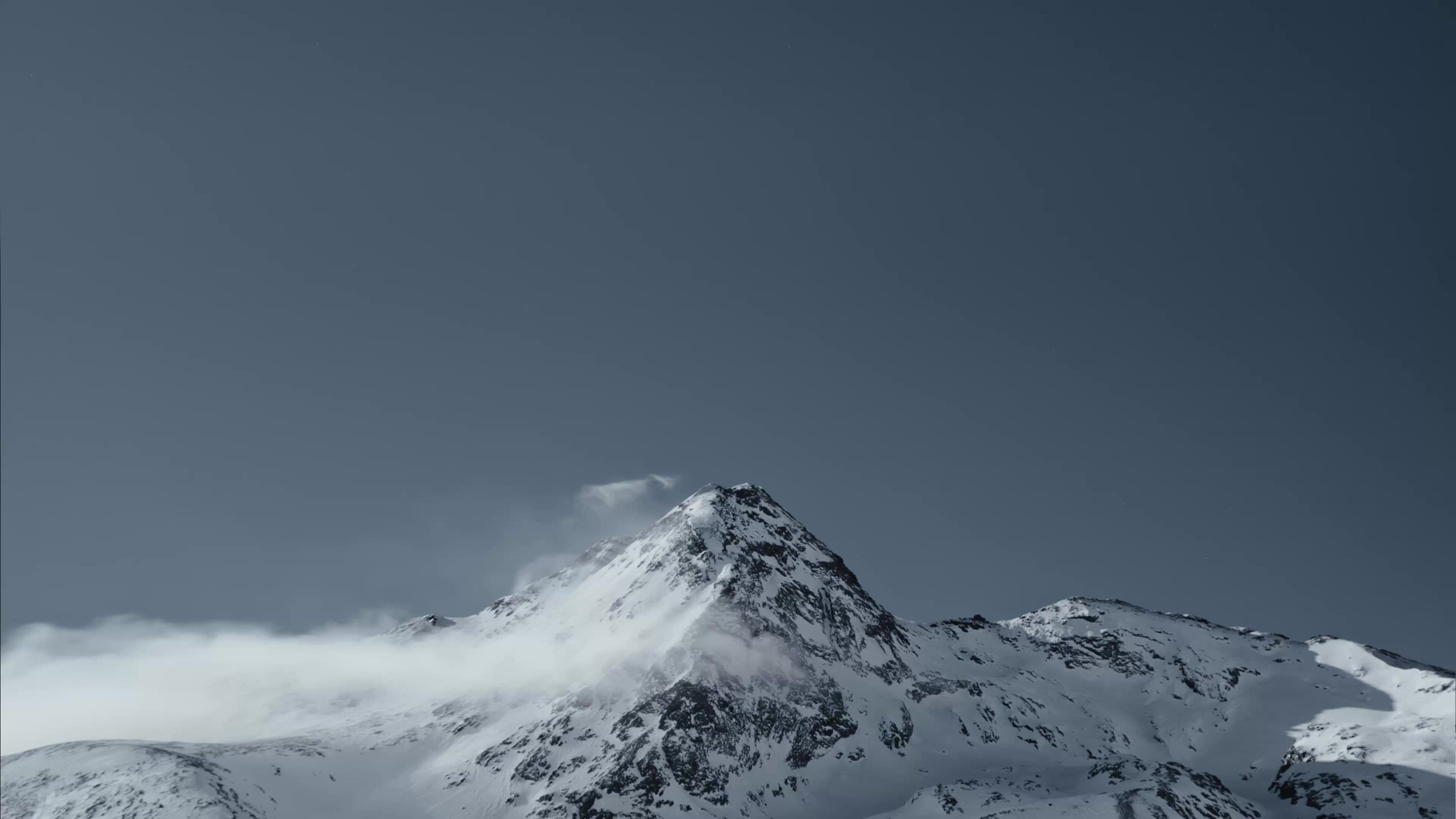An alpine mountain stands in front of a deep blue sky.