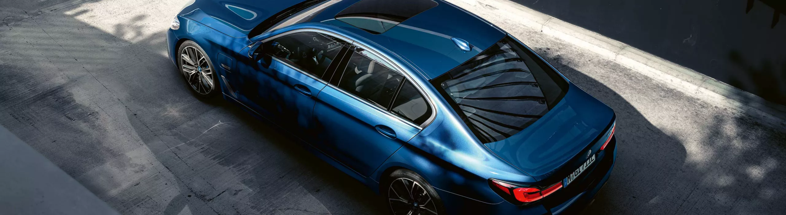 Blauer BMW wird aus erhöhter Perspektive auf einer Straße gezeigt.